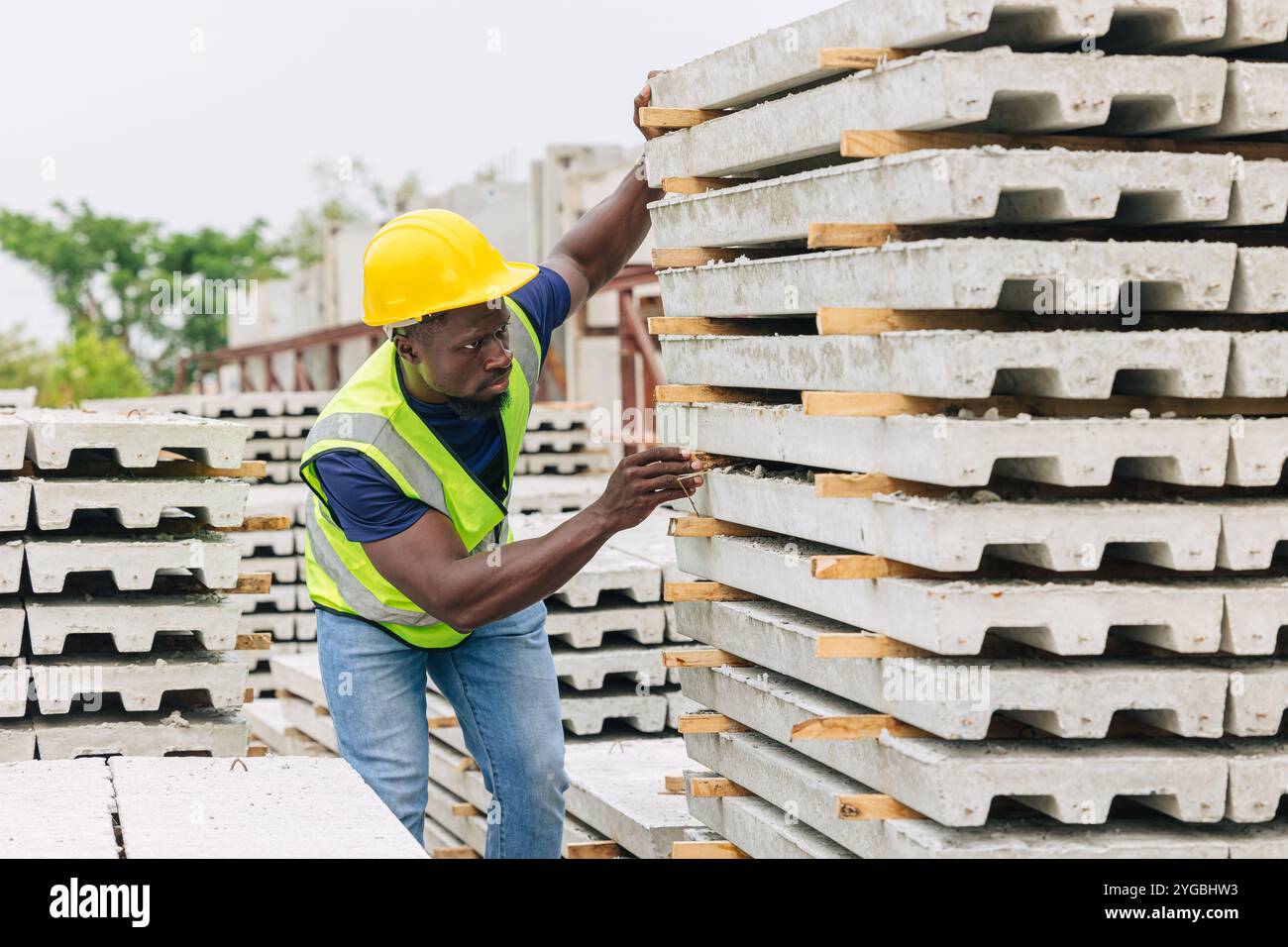 Afrikanischer schwarzer Arbeiter, der in einer Betonfertigteilfabrik arbeitet, überprüft die Qualität der Produktion vor Ort. Stockfoto