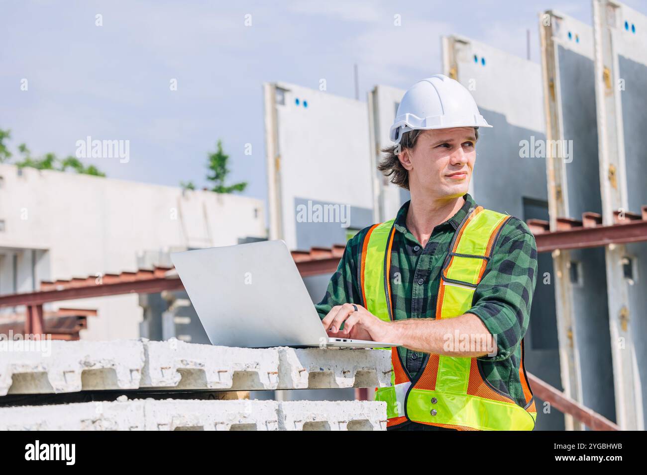 Professioneller Ingenieur kaukasischer Mann, der in Betonfertigteilwerk Fabriksteuerung arbeitet, betreibt Baustelle. Stockfoto