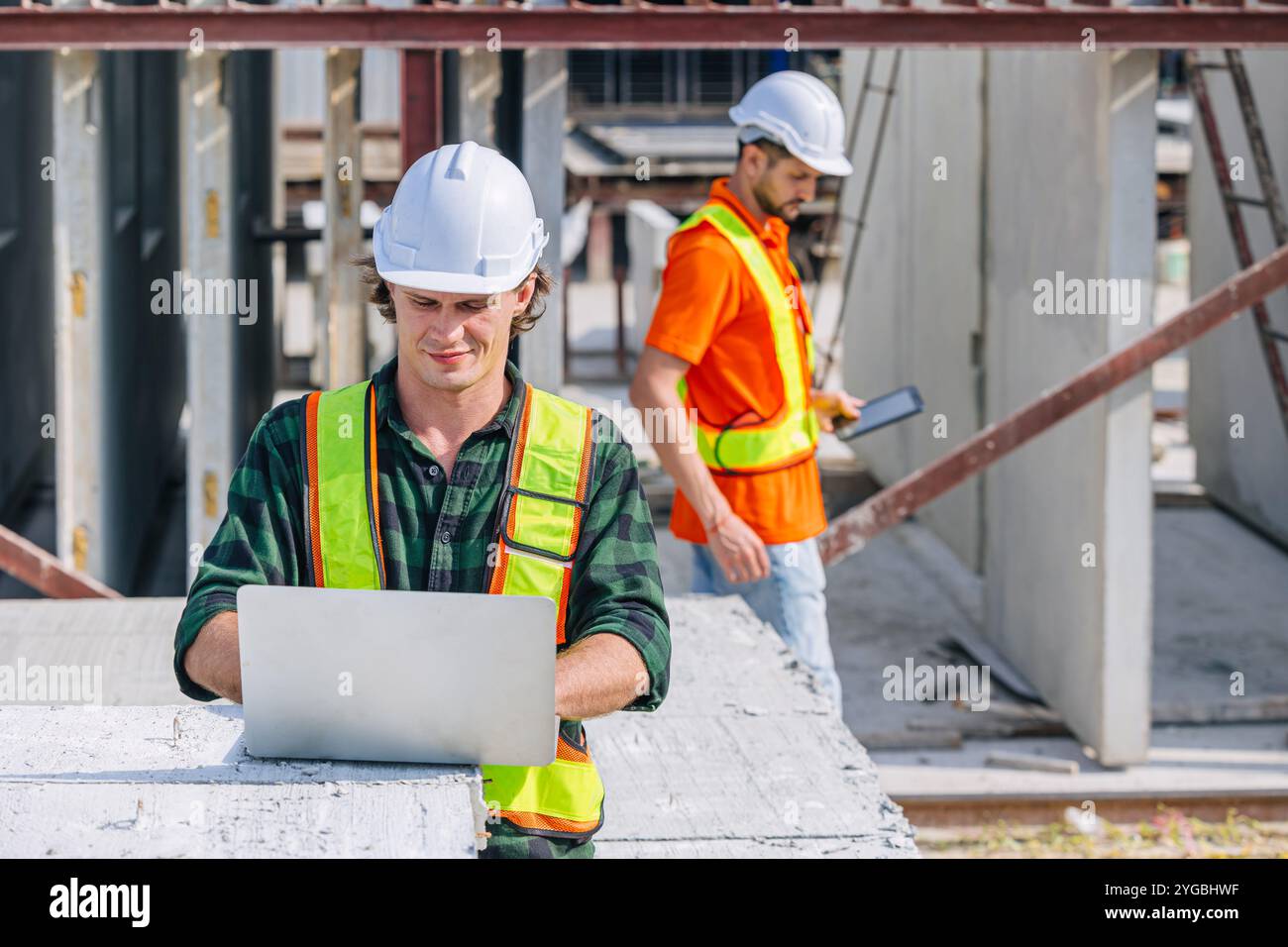 Professioneller Ingenieur kaukasischer Mann, der in Betonfertigteilwerk Fabriksteuerung arbeitet, betreibt Baustelle. Stockfoto