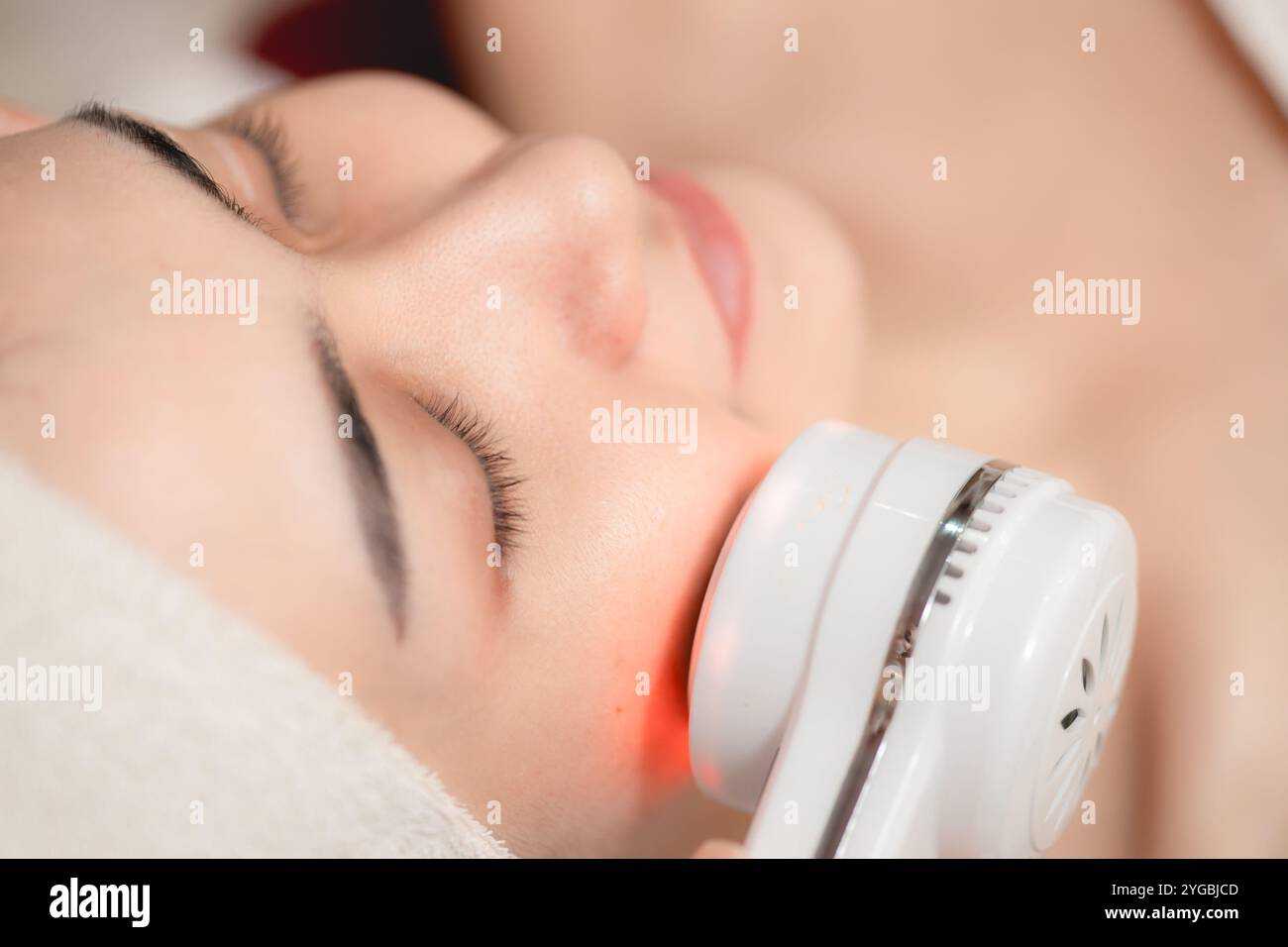 Gesichtskosmetik mit Ultraschall-Laser-Hautglühen-Verfahren. Junge Frauen sehen sich der Skin Spa-Technologie gegenüber. Stockfoto