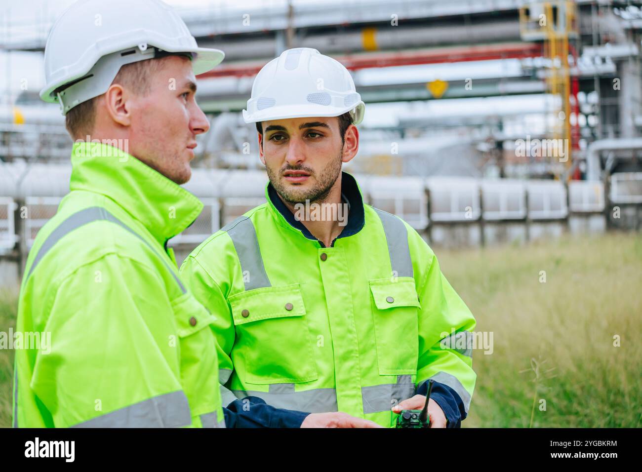 Junger Ingenieur, der sich mit dem Pipelineservice in der Erdölindustrie beschäftigt, spricht mit dem fachkundigen Manager für den Pipelineservice in der Erdölraffinerie. Stockfoto