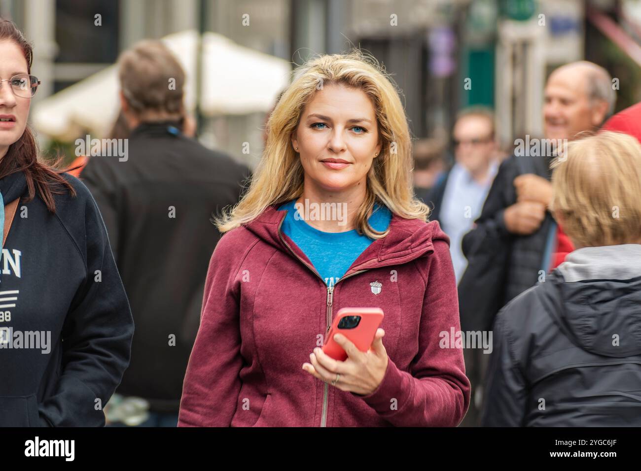 Straßenporträt von Dublins Frau. Eine blonde junge Frau in roter Jacke läuft in der Dublin Street. Dublin, Irland. Stockfoto