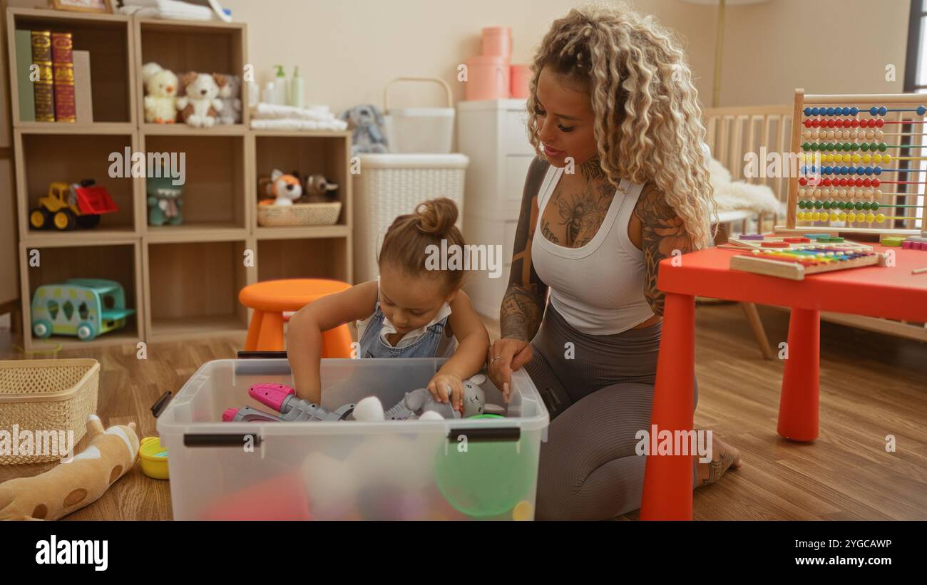 Mutter und Tochter spielen mit Spielzeug in einem Kindergartenspielzimmer, umgeben von Büchern, Kuscheltieren und Lernspielzeug. Stockfoto