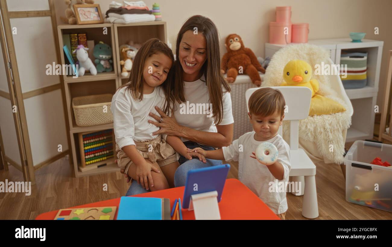 Frau, umgeben von Sohn und Tochter, in einem gemütlichen Spielzimmer voller Spielzeuge, in dem die Liebe der Familie in einer fröhlichen Atmosphäre im Kindergarten-Schoo umrahmt wird Stockfoto