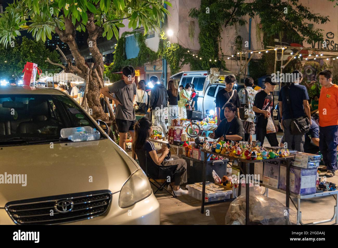 Blick auf einen Spielzeugstand vor dem Auto des Verkäufers, auf dem Green Vintage Market in Ratchayothin, Bangkok. Der Green Vintage Market in Ratchayothin, Bangkok, ist ein Outdoor-Markt, der für seine eklektische Mischung aus Vintage-Waren und Kunsthandwerk bekannt ist. Mit seiner Bohème-Atmosphäre bietet der Markt auch einen Bereich, der auf Vintage- und Sammlerspielzeug spezialisiert ist, wo Spielzeugsammler und -Enthusiasten seltene Actionfiguren, Modellautos, klassische Puppen, Anime-Figuren und andere nostalgische Schätze finden können. (Foto: Nathalie Jamois/SOPA Images/SIPA USA) Stockfoto