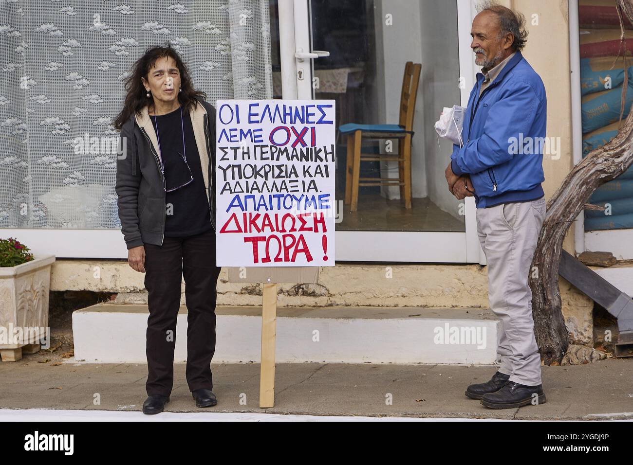 Zwei Personen auf einem Protest, mit einem Schild mit Forderungen in griechischer Sprache, Besuch von Bundespräsident Frank-Walter Steinmeier in Kandanos am 31. Oktober 2024, Fede Stockfoto