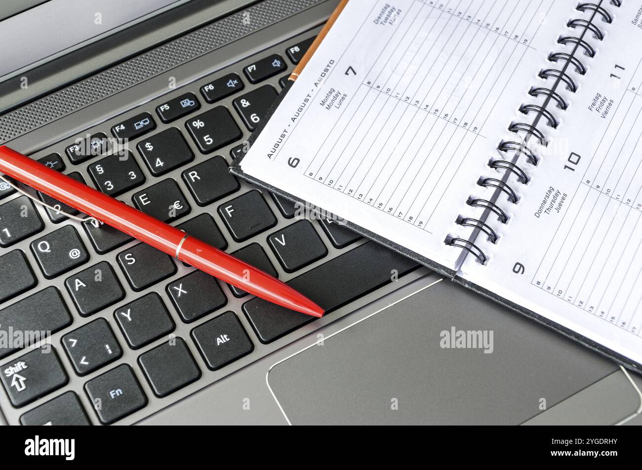Roter Stift und Zeitplan liegen auf Laptop-Tastatur Stockfoto