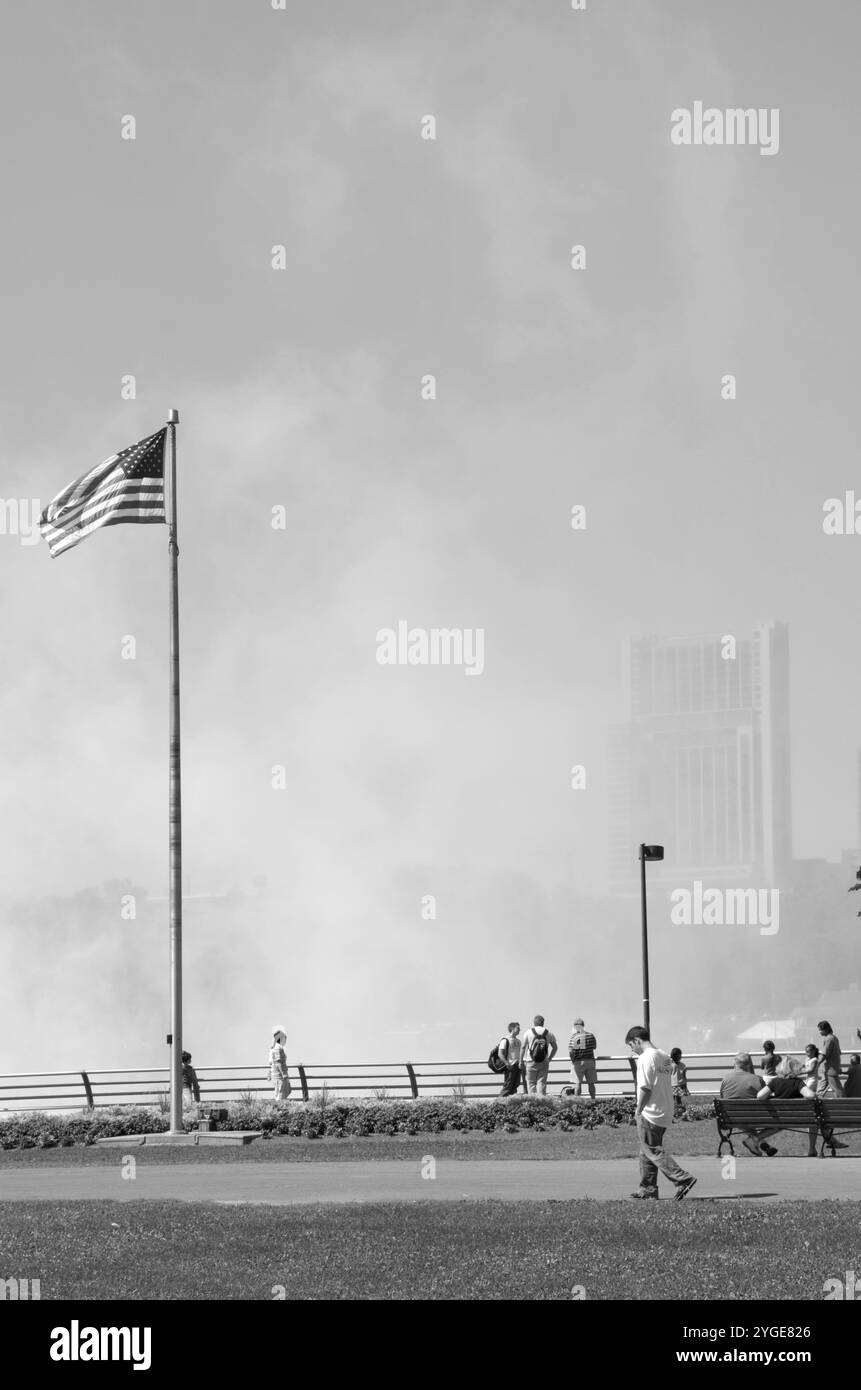 Touristen, die im Niagara Falls State Park, New York, USA, spazieren gehen und die amerikanische Seite der Niagarafälle bewundern. Stockfoto