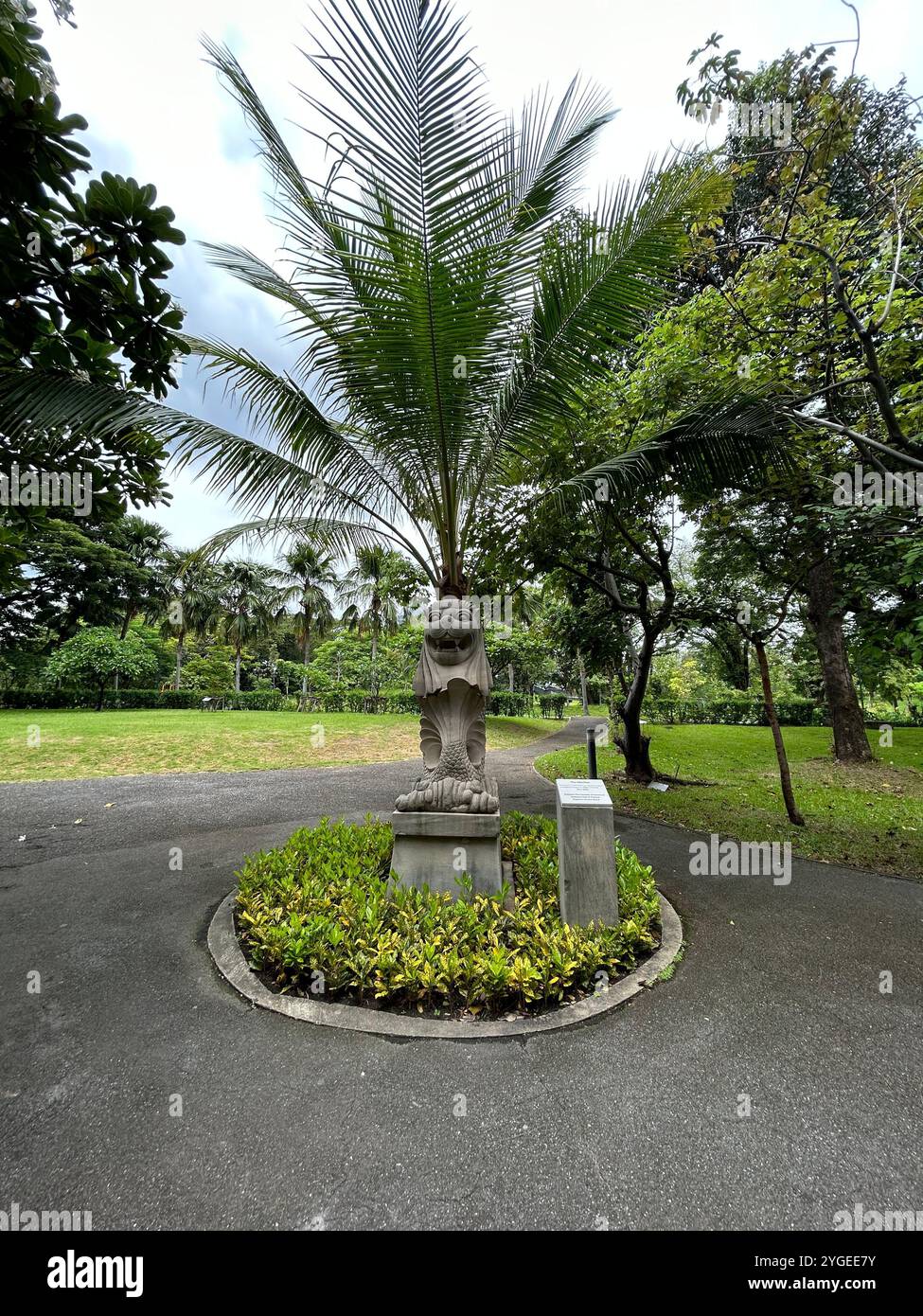 parkszene mit einer einzigartigen Sonnenuhr-Skulptur und einem modernen Wolkenkratzer im Hintergrund, die Natur und städtische Architektur miteinander verbindet. Stockfoto