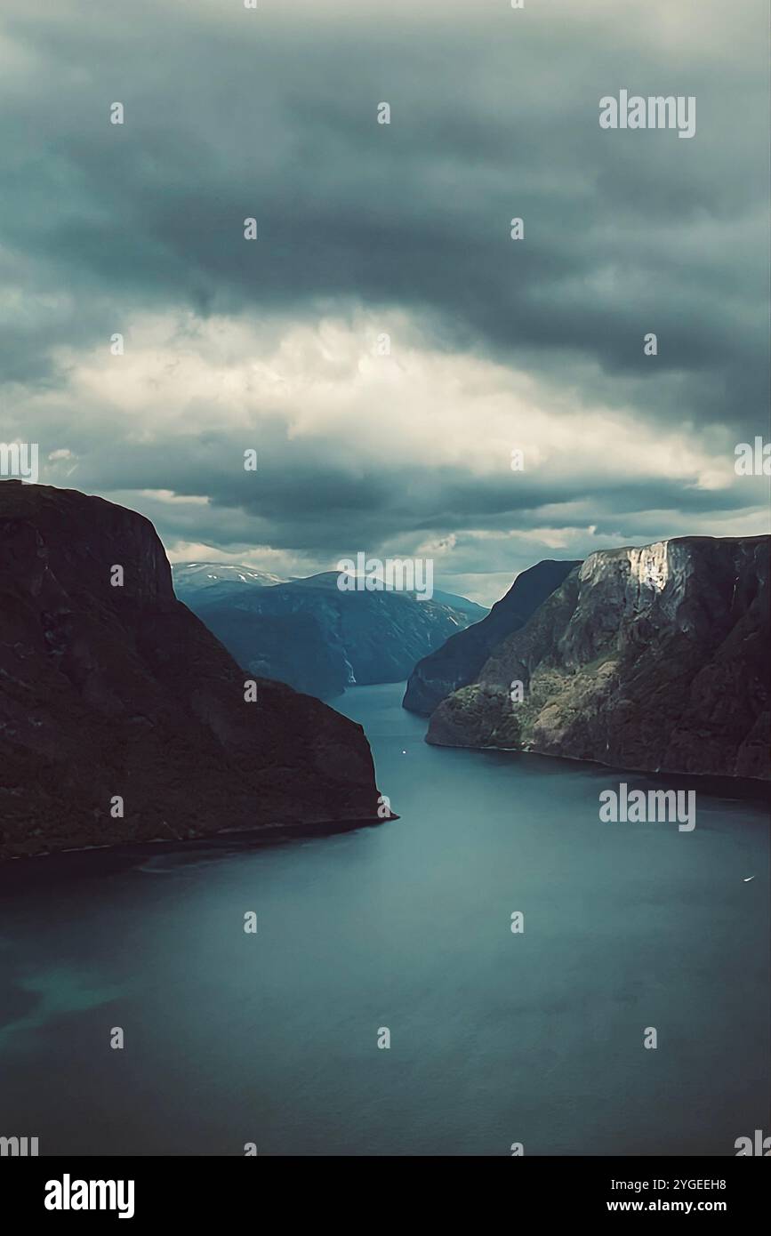 Genießen Sie die stille Majestät der norwegischen Fjorde, wo hoch aufragende Klippen auf tiefes, ruhiges Wasser unter dramatischem Himmel treffen. Stockfoto