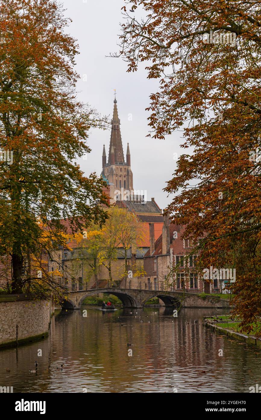 Der Turm der Kirche unserer Lieben Frau Brügge und die Lovers Bridge am Minnewater See, Lovers Lake, Brügge, Belgien im Oktober Stockfoto