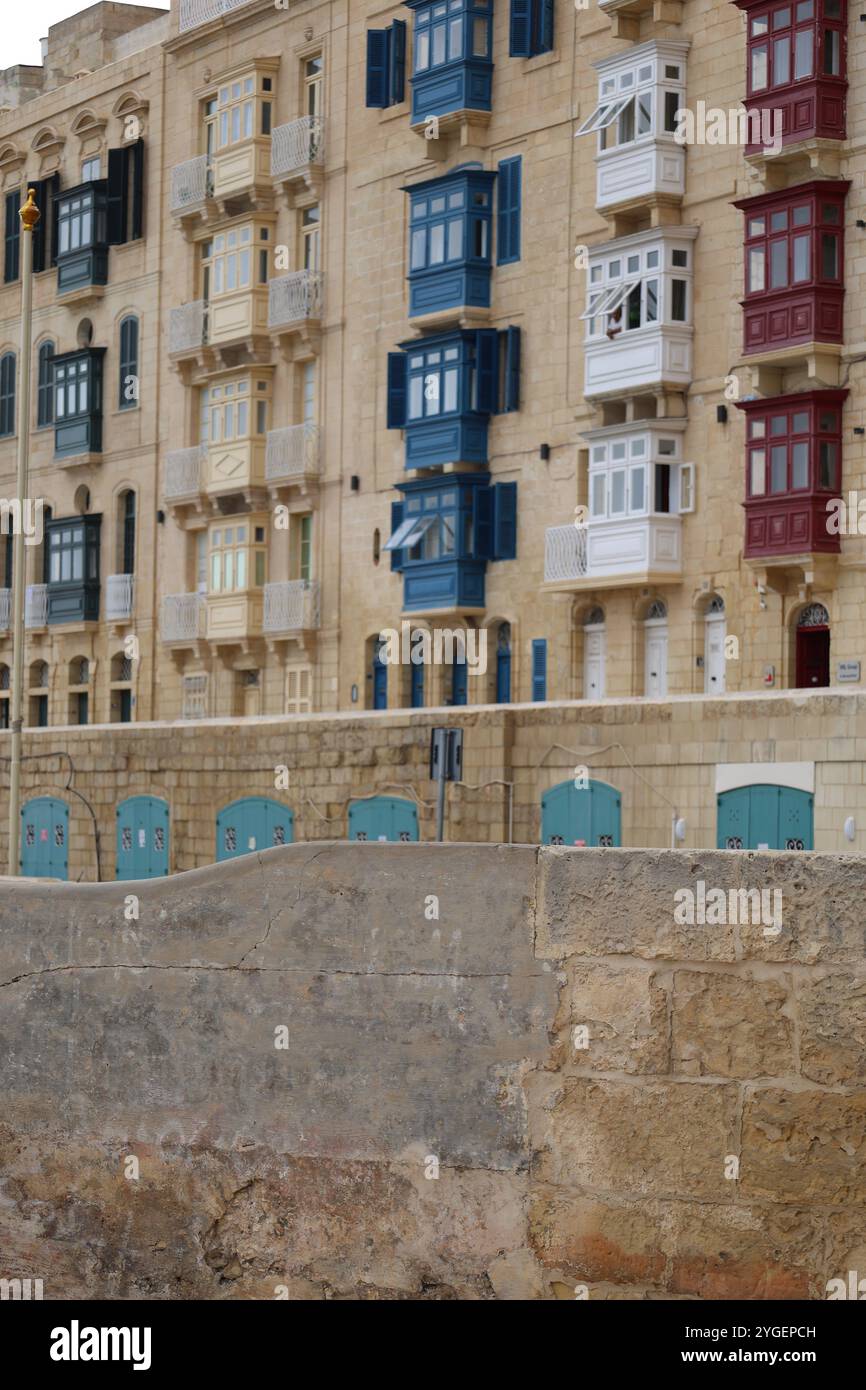 Valletta. Malta. Häuserreihe. Erker. Bunt. Wasserfront. Kalkstein. Reihe von Häusern. bay-Fenster. Farbenfroh. Uferpromenade. Kalkstein. Tür. Balkon. Anschnitt. Stockfoto