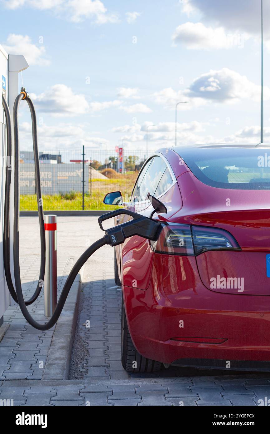 Roter vollelektrischer Tesla Model 3 an der Ladestation in Litauen Stockfoto