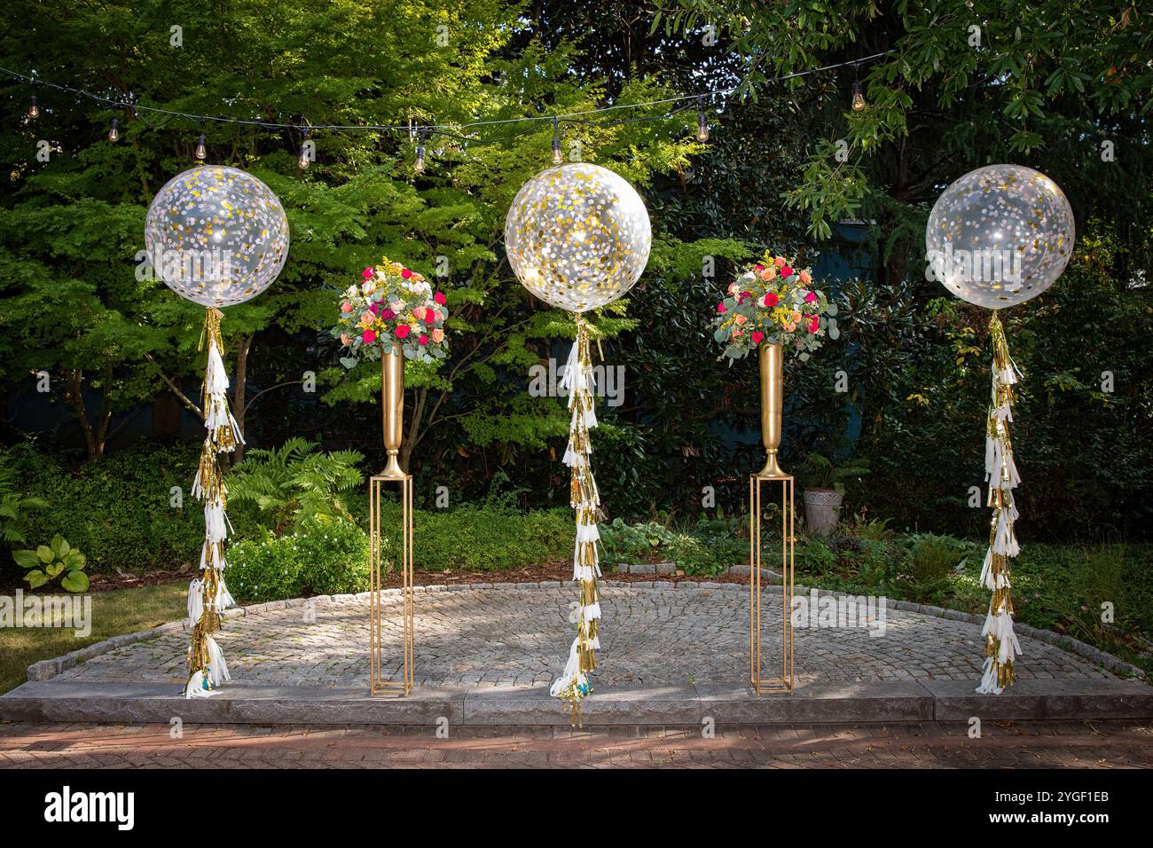 Elegante Hochzeitsdekoration im Freien mit Ballons und Blumenarrangements in einem malerischen Garten Stockfoto