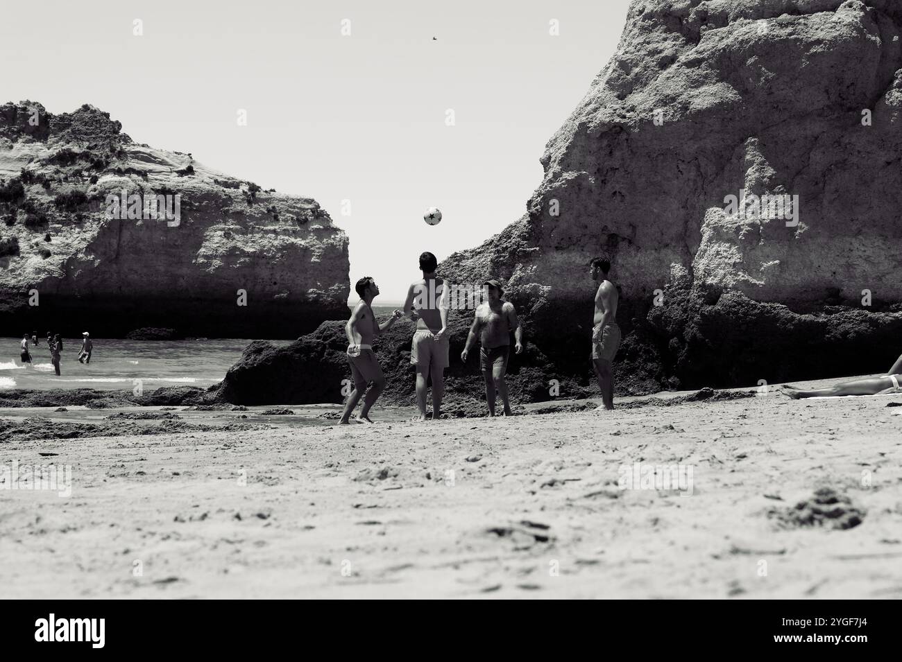 Riten spielen Strandfußball an den felsigen Ufern von praia da rocha, in Schwarz-weiß gefangen Stockfoto