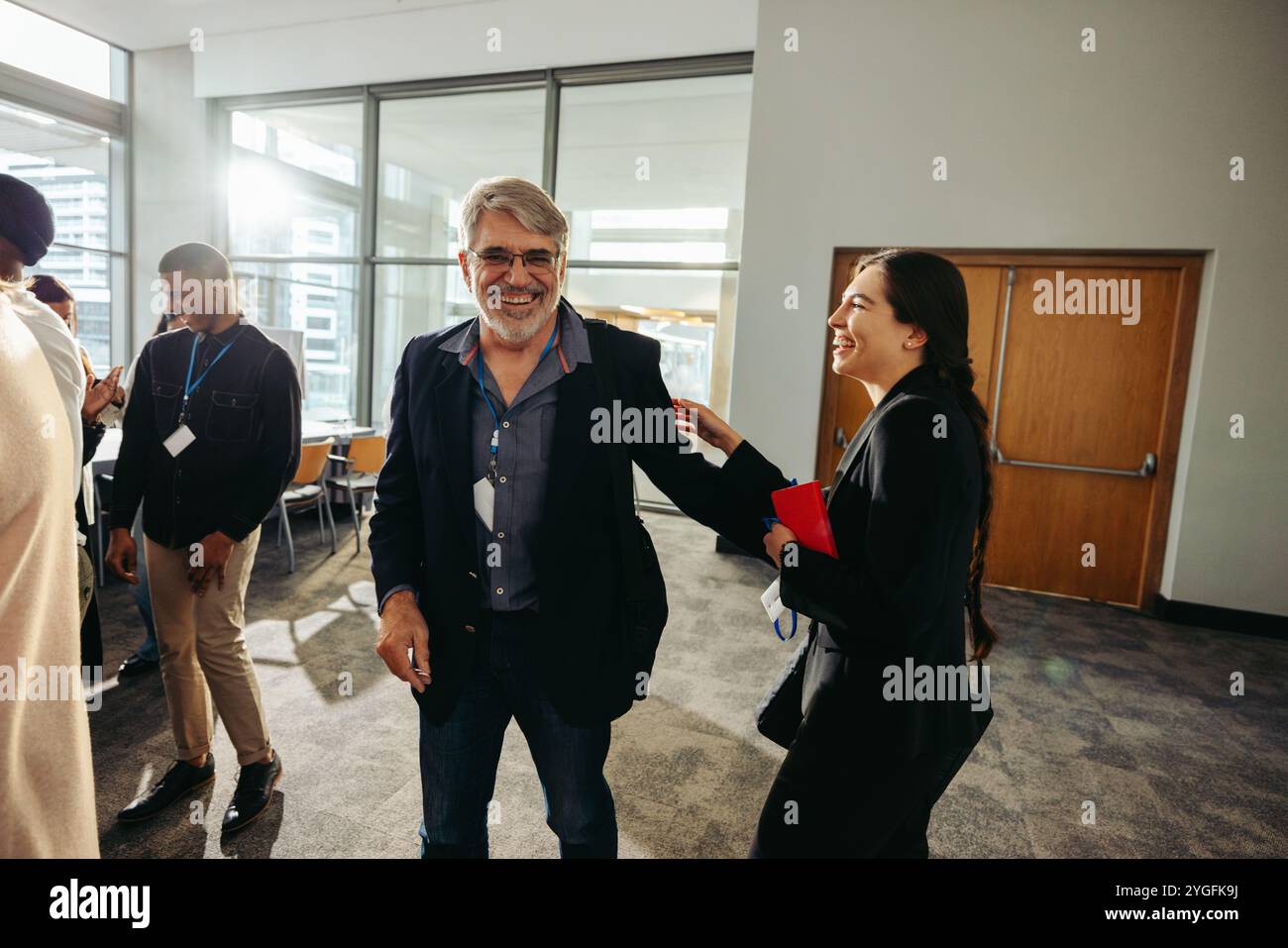Glückliche Kollegen aus verschiedenen Altersgruppen, die bei einer Konferenz interagieren und verschiedene Generationen und Teamwork hervorheben. Stockfoto
