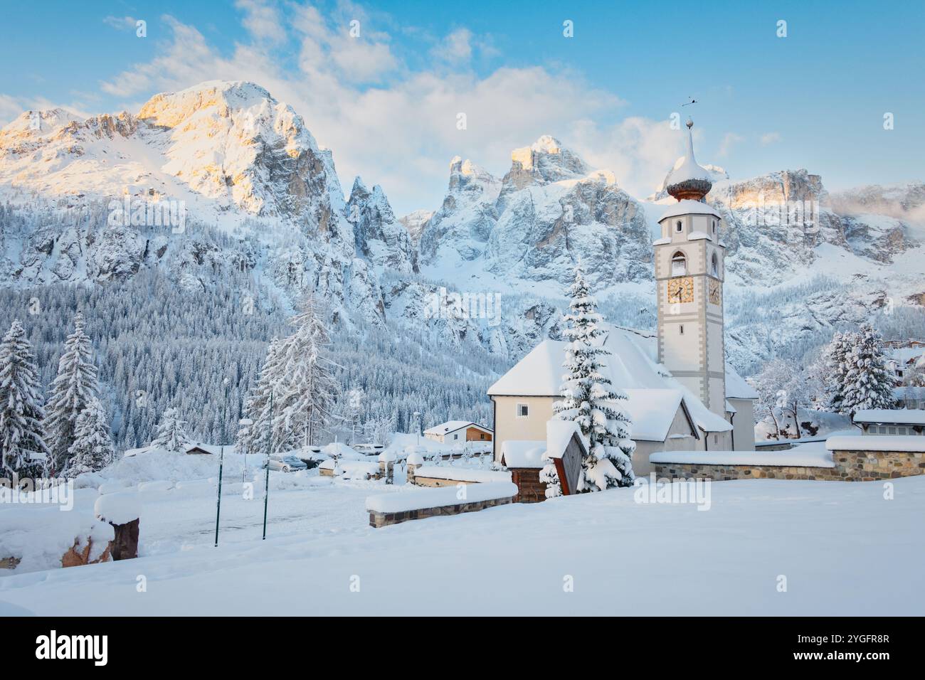 Die markante Kirche von Kolfuschg bei Corvara mit der Sellagruppe Dolomiten unter einer frischen Schneedecke in Alta Badia, Italien. Stockfoto