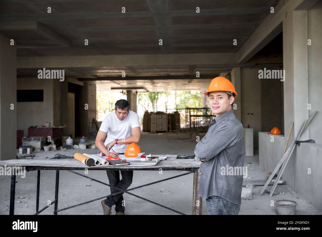 Architekt, Ingenieur, Auftragnehmer oder Bauleiter, der mit einem Armkreuz auf einer Baustelle steht. Stockfoto