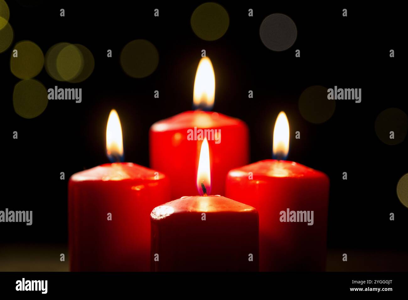 Vier brennende rote Kerzen auf festlichem schwarzem Hintergrund mit goldener Dekoration, Nahaufnahme. Adventskonzepte, Weihnachten, Feiertage und Tradition. Stockfoto