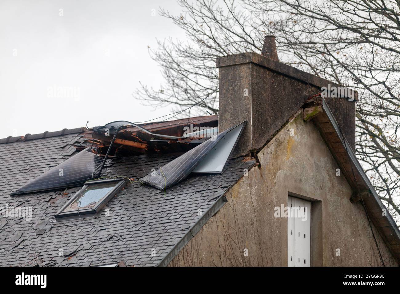 Das Dach eines Hauses wurde beschädigt, nachdem die Solarpaneele des gegenüber liegenden Gebäudes abgerissen wurden und während eines Herbststors etwa 50 Meter bei 106 mph zurückgelegt wurden Stockfoto