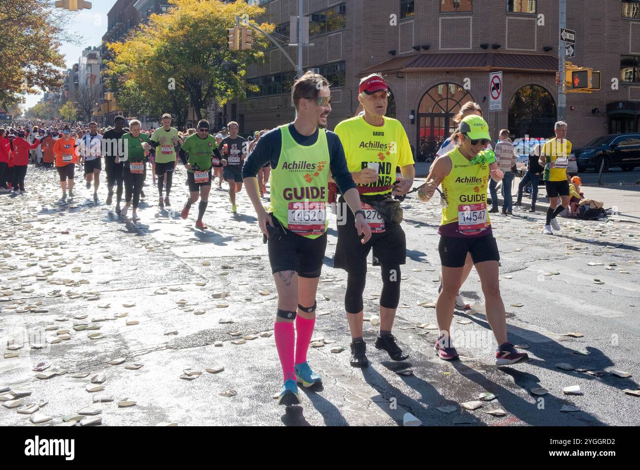 Ein blinder Läufer wird von 2 Freiwilligen von Achilles International durch den NY Marathon 2024 geführt. Stockfoto