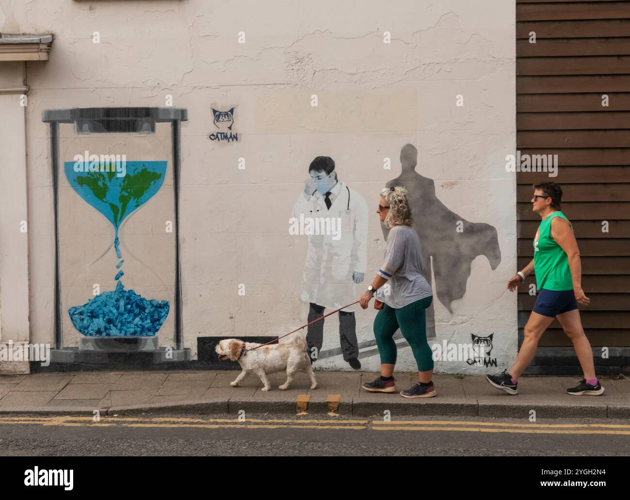 England, Kent, Whitstable, Straßenszene mit zwei Frauen, die an Wall Art vorbeilaufen Stockfoto