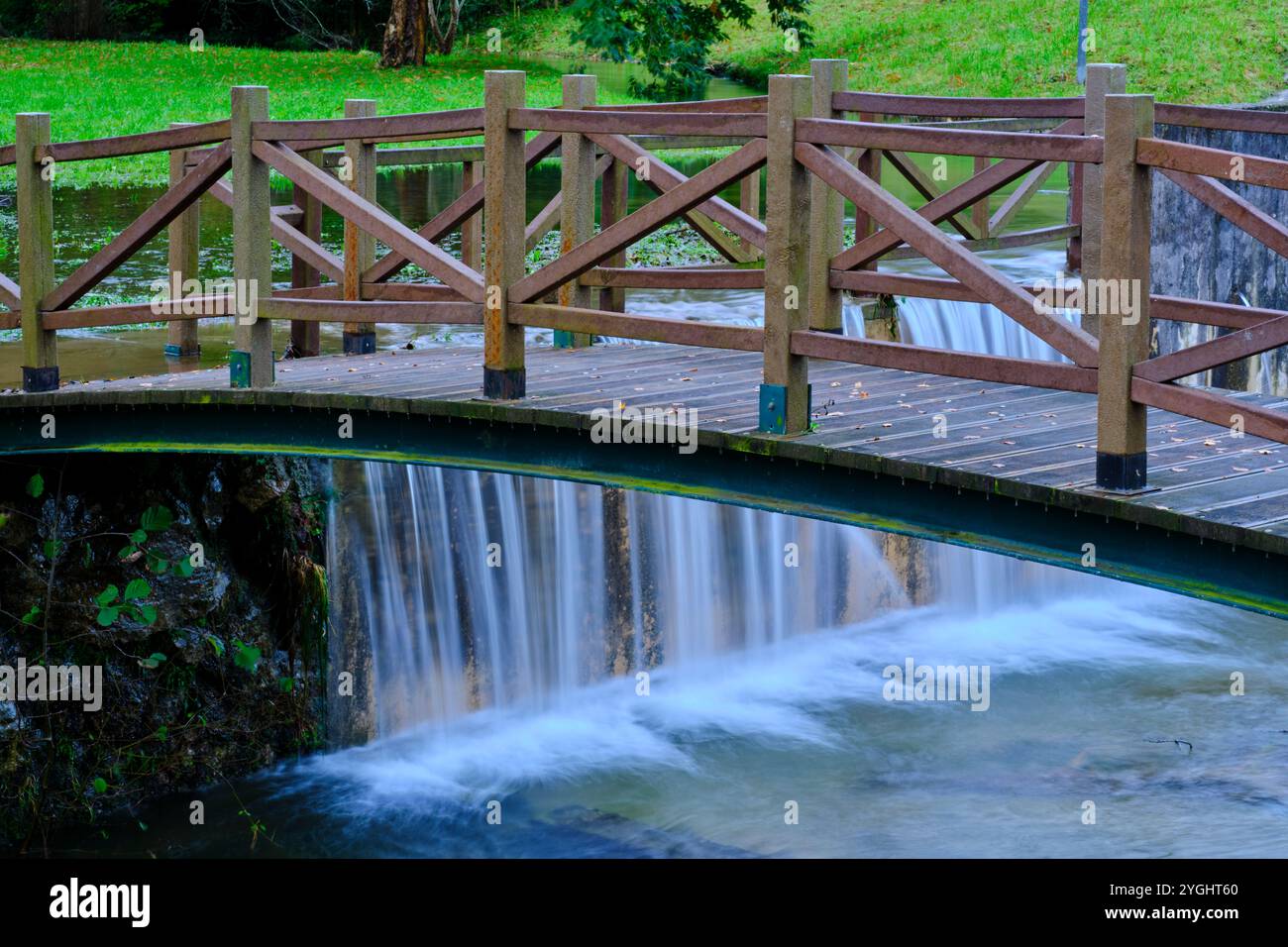 Nahaufnahme einer hölzernen Brücke über einen kleinen Wasserfall im Fluss Saja, in Cabezon de la Sal, Kantabrien. Spanien. Stockfoto