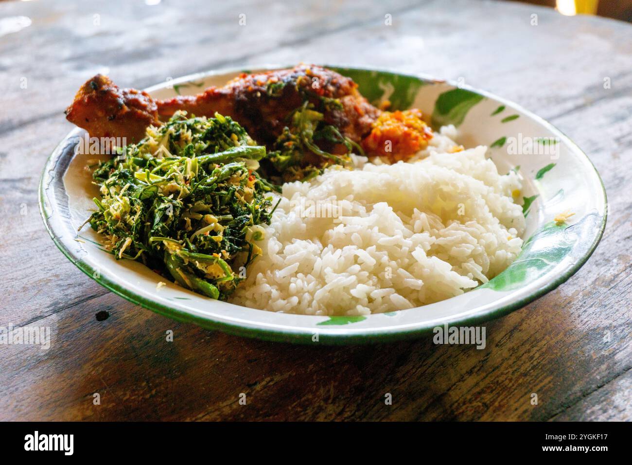 Indonesisches Gericht. Reis mit Urap-Urap (indonesischer Salat mit Chili, geriebener Kokos und anderen Gewürzen) und gebratenem Huhn Stockfoto