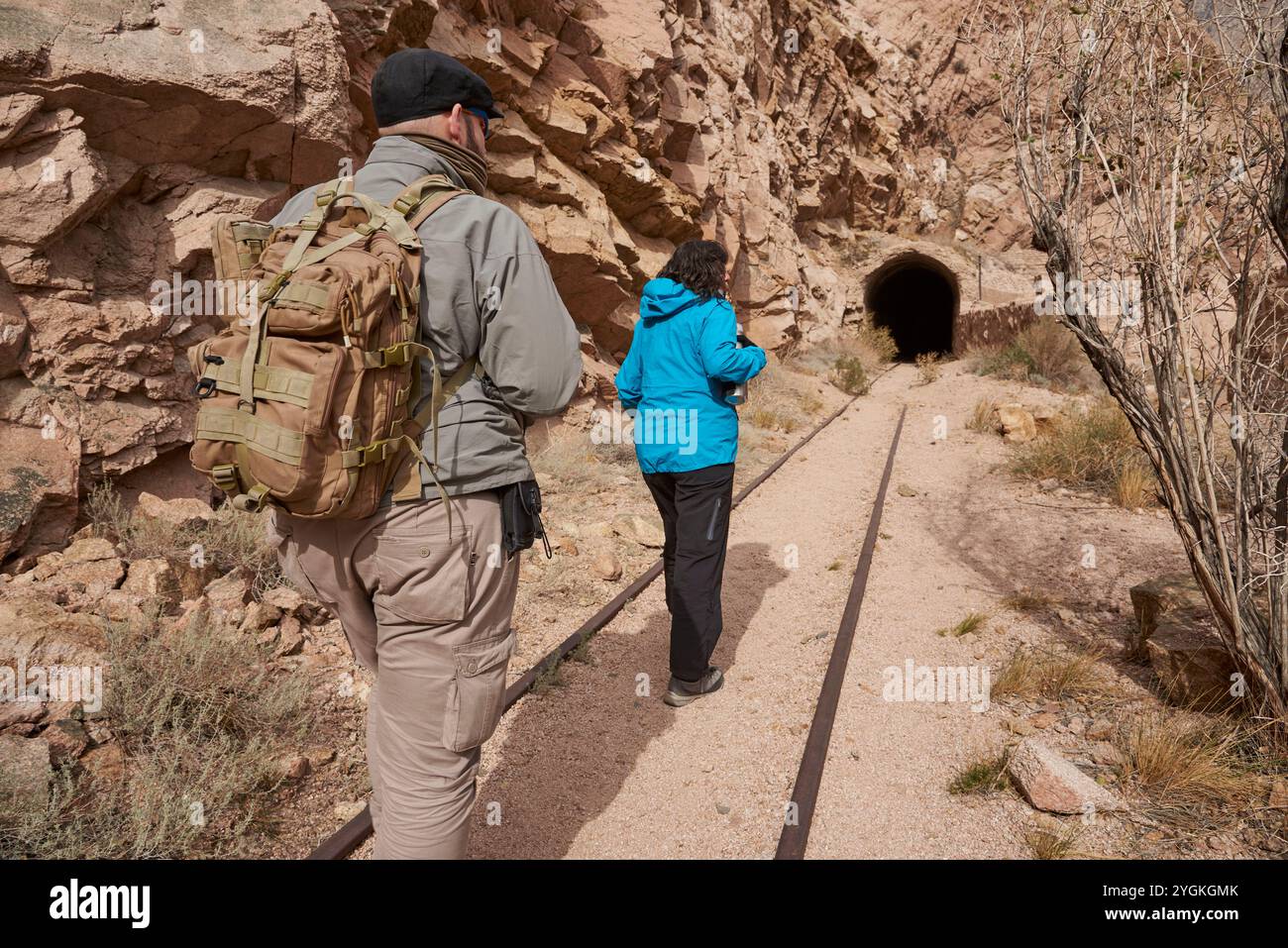 Ein paar Freunde, Mann und Frau, laufen auf den Gleisen in einer bergigen Gegend von Potrerillos, Mendoza, Argentinien. Im Hintergrund gibt es ein t Stockfoto