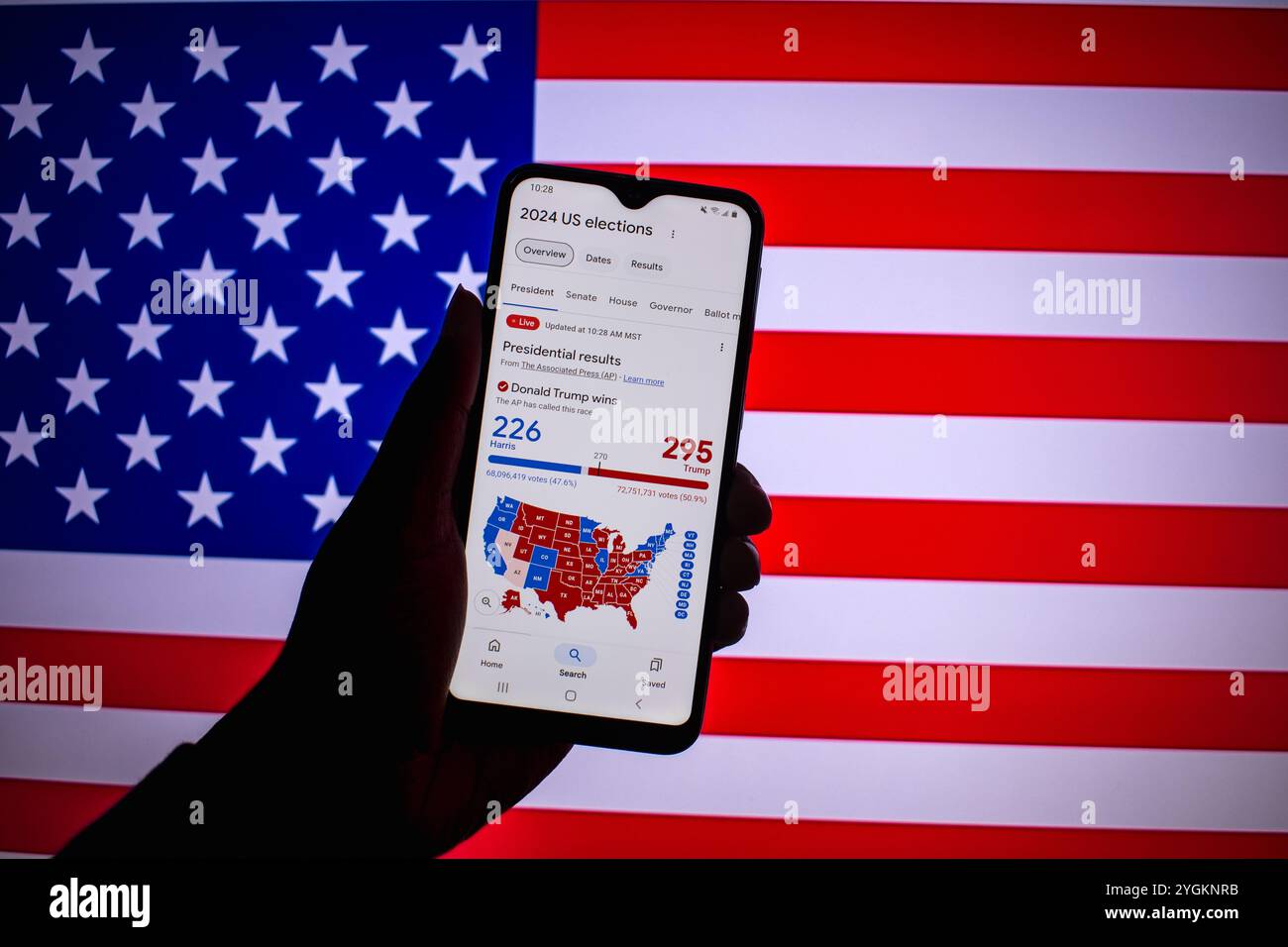 Ein Mann hält ein Smartphone, das die Ergebnisse der Wahlen in den Vereinigten Staaten von 2024 anzeigt. Der Kandidat der Republica Donald Trump gewann die Wahlen. Stockfoto