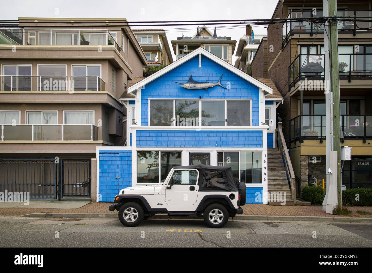 Ein farbenfrohes blaues Haus mit großer Marlin-Fisch-Dekoration auf der Außenseite auf dem Marine Way mit weißem Jeep davor geparkt. Stockfoto