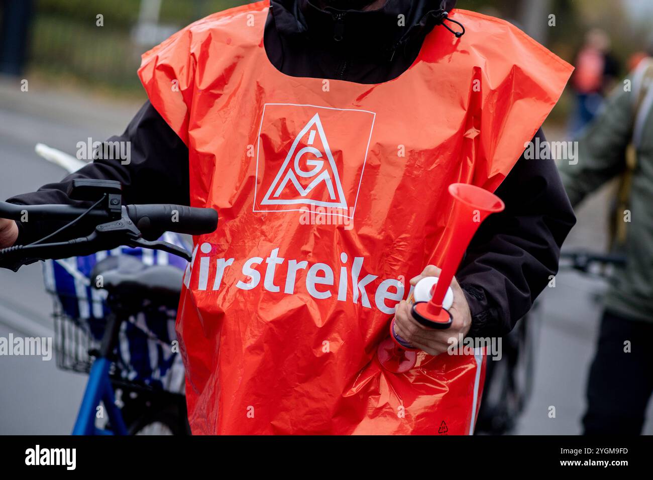 Bremen, Deutschland. November 2024. Ein Mercedes-Benz Mitarbeiter mit IG Metall-Weste und Hornbläser nimmt an einem demonstrationsmarsch vom Werk nach Osterdeich Teil. Die Warnmeldungen in der Metall- und Elektroindustrie gehen weiter. Die IG Metall will den Druck im aktuellen Lohnstreit erhöhen. Quelle: Hauke-Christian Dittrich/dpa/Alamy Live News Stockfoto