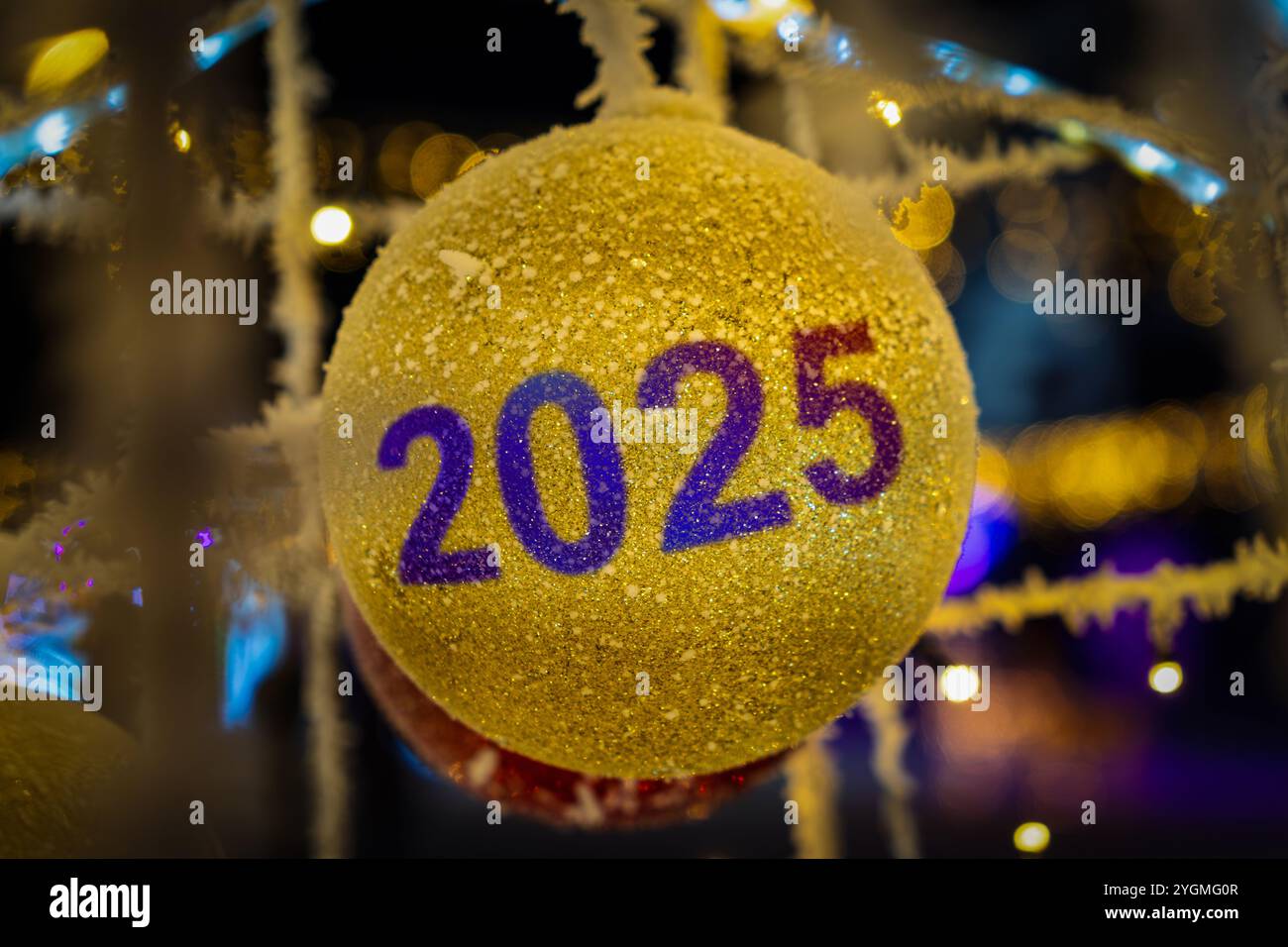 Eleganter Weihnachtsbaum mit goldenen Ballons. Ein gelbes Weihnachtsspielzeug mit der Nummer 2025. Der Beginn des neuen Jahres. Stockfoto
