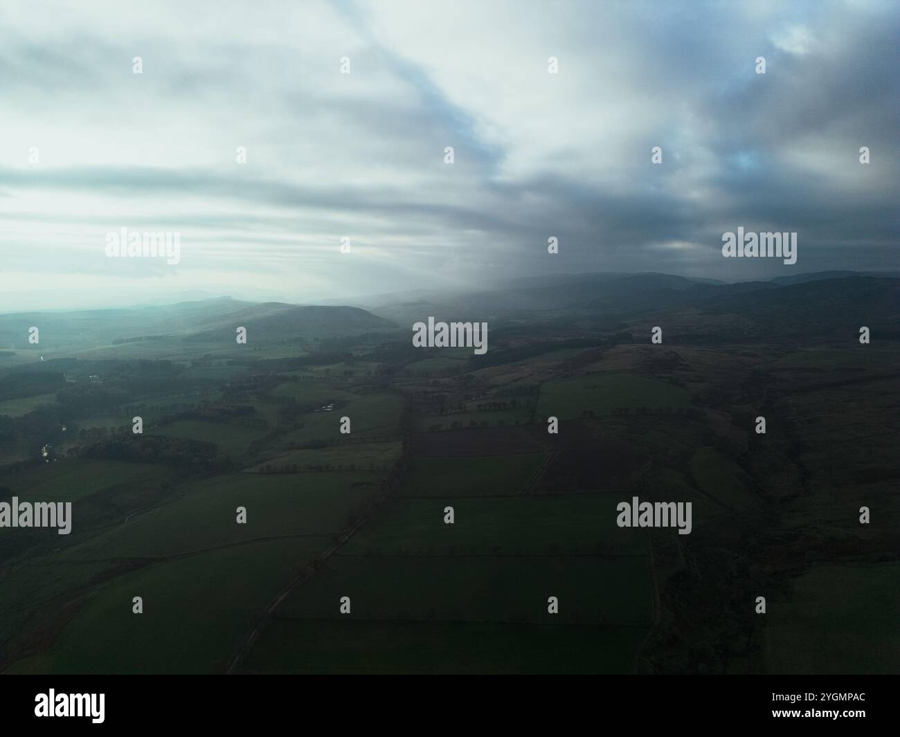 Neblige, weitläufige ländliche Landschaft mit sanften Hügeln und bewölktem Himmel, die die Schönheit der Natur in einer stimmungsvollen, stimmungsvollen Szene zeigt. Stockfoto