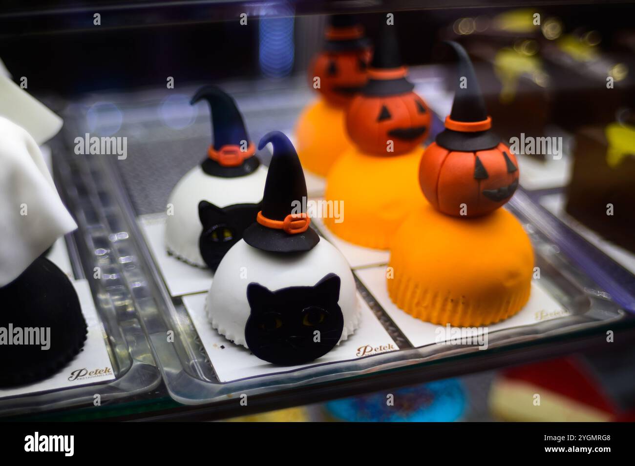 Entzückende Halloween-Leckereien in Form von Katzen und Kürbissen, die in einer Bäckerei präsentiert werden und zu festlichen Feiern einladen. Stockfoto