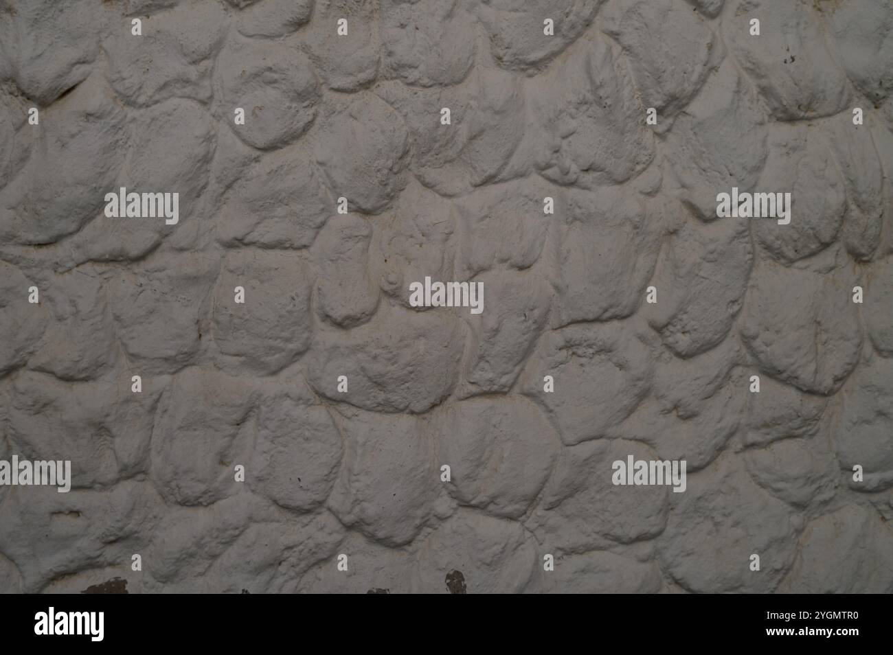 Die Oberfläche zeigt eine strukturierte Steinmauer mit einer weichen, leichten Oberfläche, die rustikale Eleganz und Geschichte verkörpert. Stockfoto