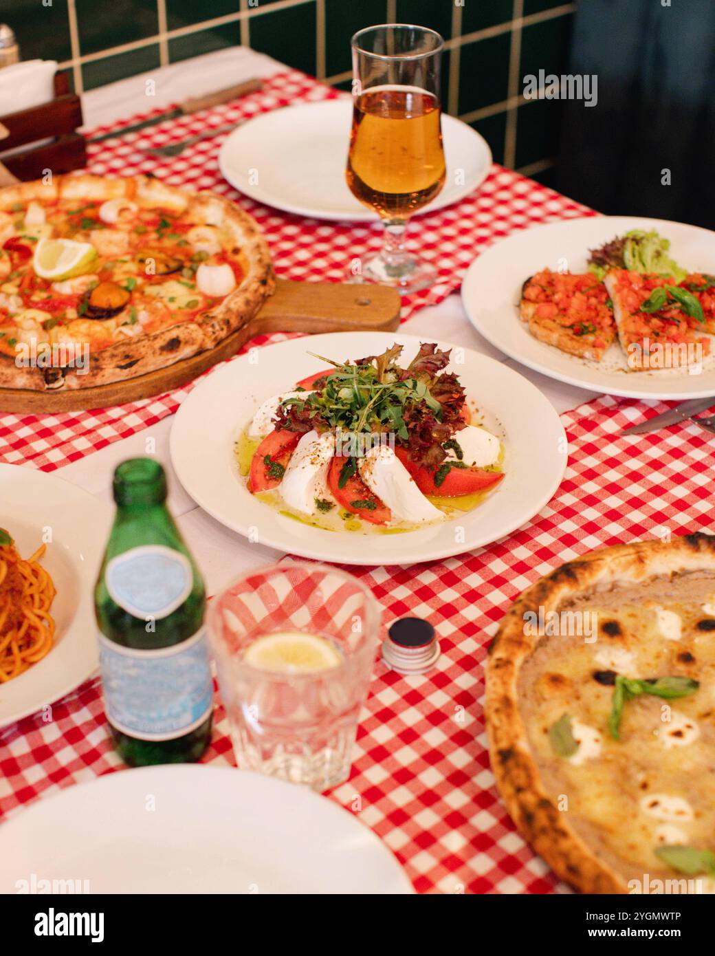 Italienisches Restaurant Tisch mit verschiedenen Pizzen, Pasta-Gerichten und Wein auf karierter Tischdecke Stockfoto