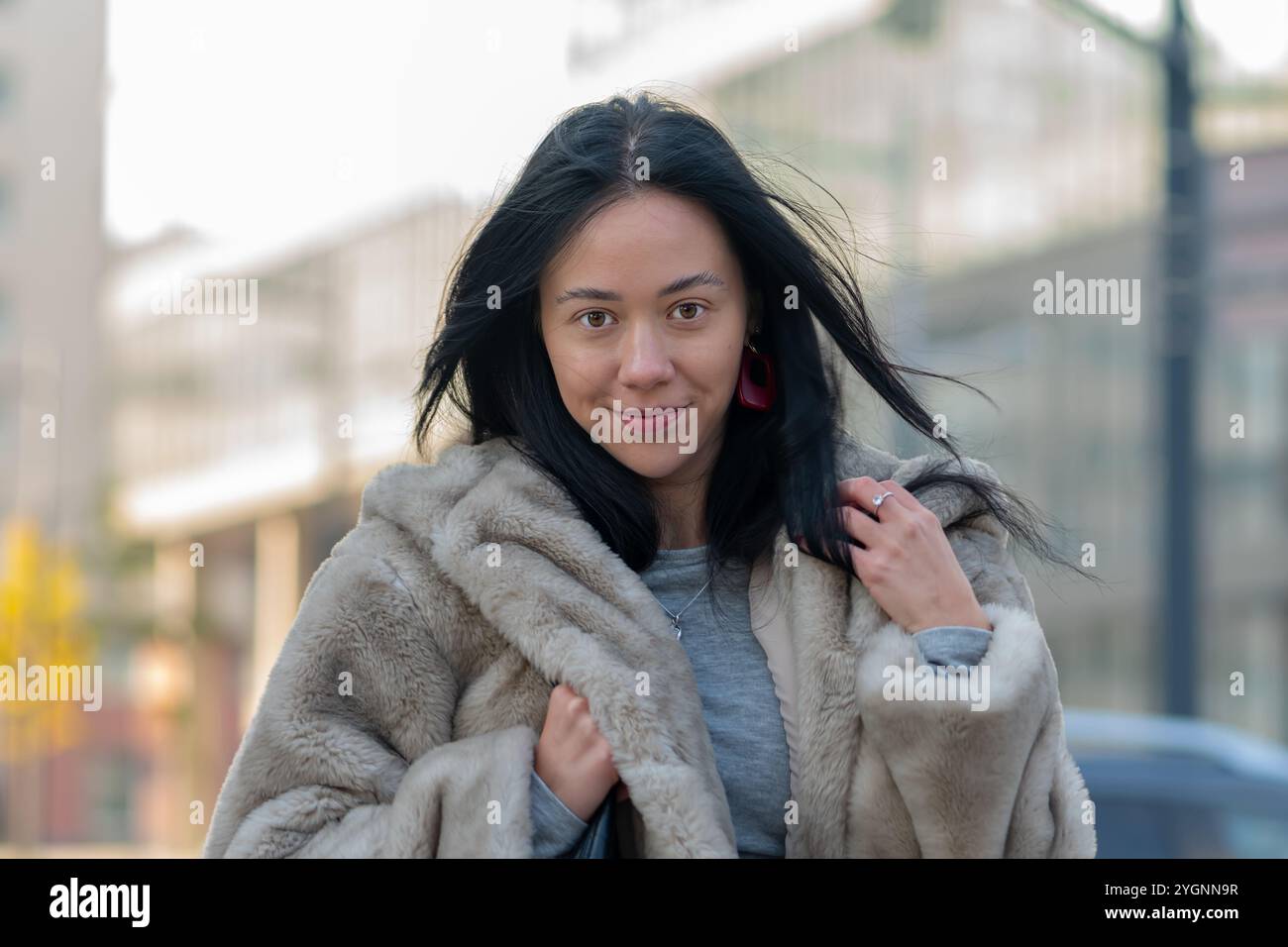 Schöne Frau mit orientalischem Aussehen 20 - 25 Jahre alt auf dem Hintergrund einer verschwommenen Stadtlandschaft. Stockfoto
