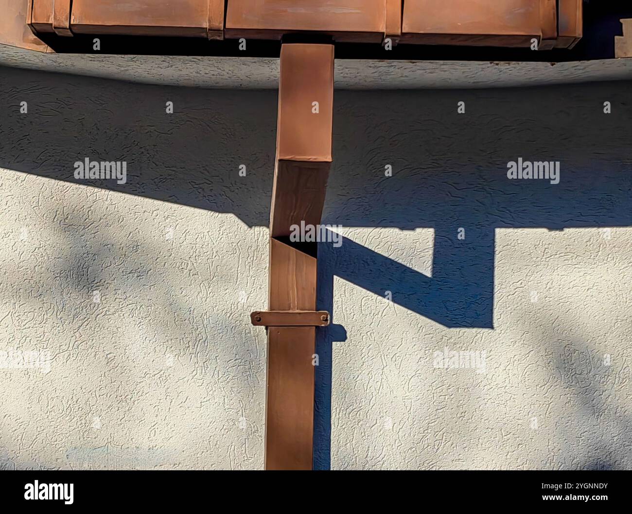 Brauner Steg für Sammel- und Kanalwasser. Schatten auf der Weißen Wand: Architektonische Nahaufnahme Stockfoto