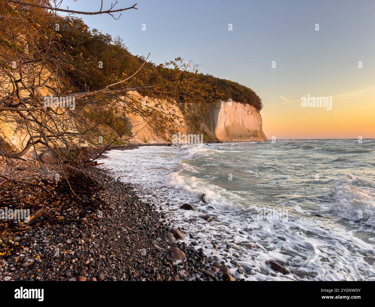 Kreidefelsen auf Rügen werden von der Sonne beleuchtet, im Vordergrund steht ein Steinstrand Stockfoto