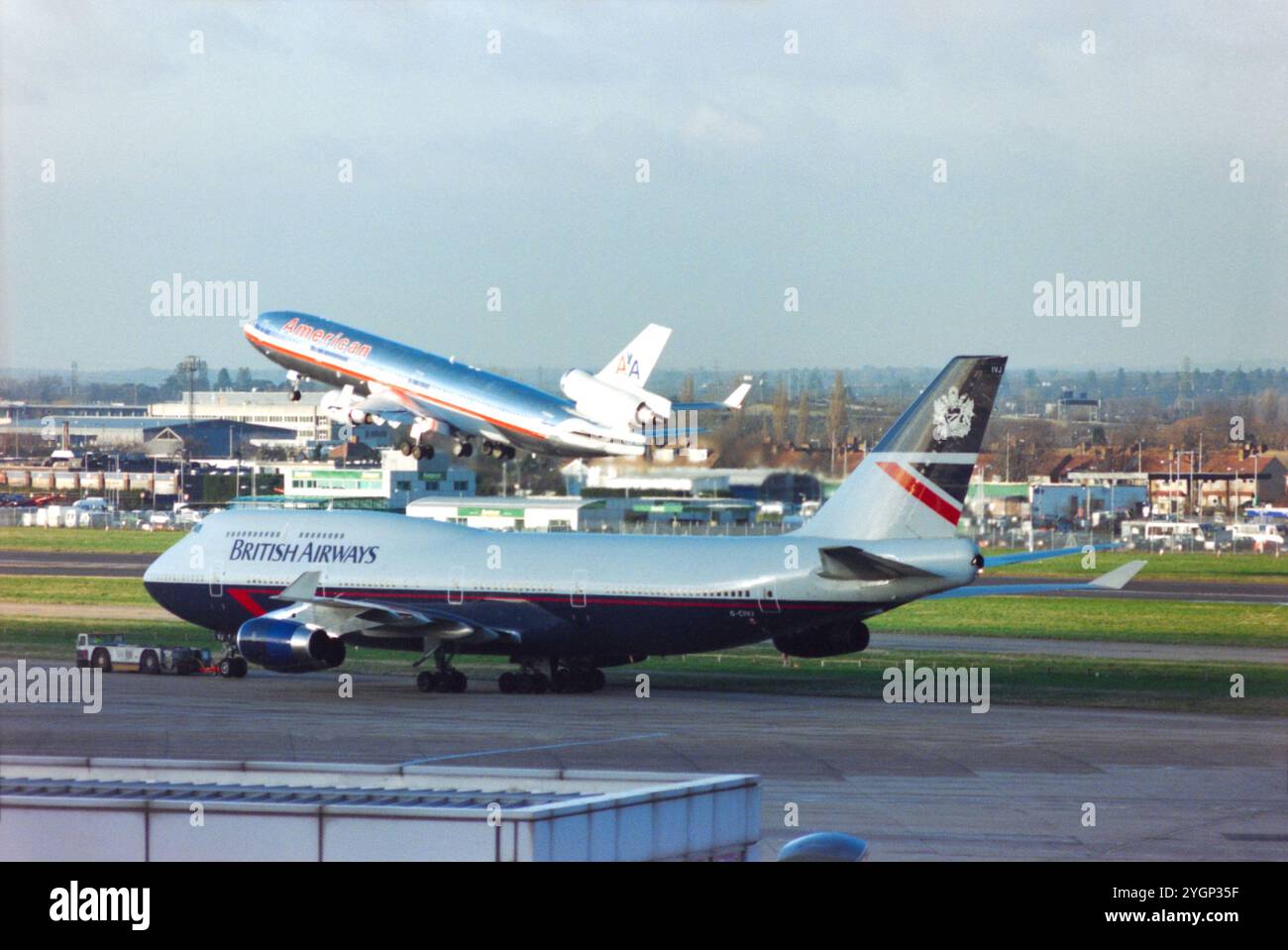 British Airways Boeing 747 Jumbo Jet Jet Flugzeug G-CIVJ in der Landor Farbgebung wird von einem Schlepper gezogen, wobei American Airlines McDonnell Douglas MD-11 Anfang 2000 vom Flughafen London Heathrow, Großbritannien, startete. 747 G-CIVJ wurde am 11. Februar 1997 neu an BA geliefert und am 15. April 2020 an Kemble zurückgezogen. American Airlines stellte ihre Flotte von MD-11-Flugzeugen 2001 aus. Stockfoto