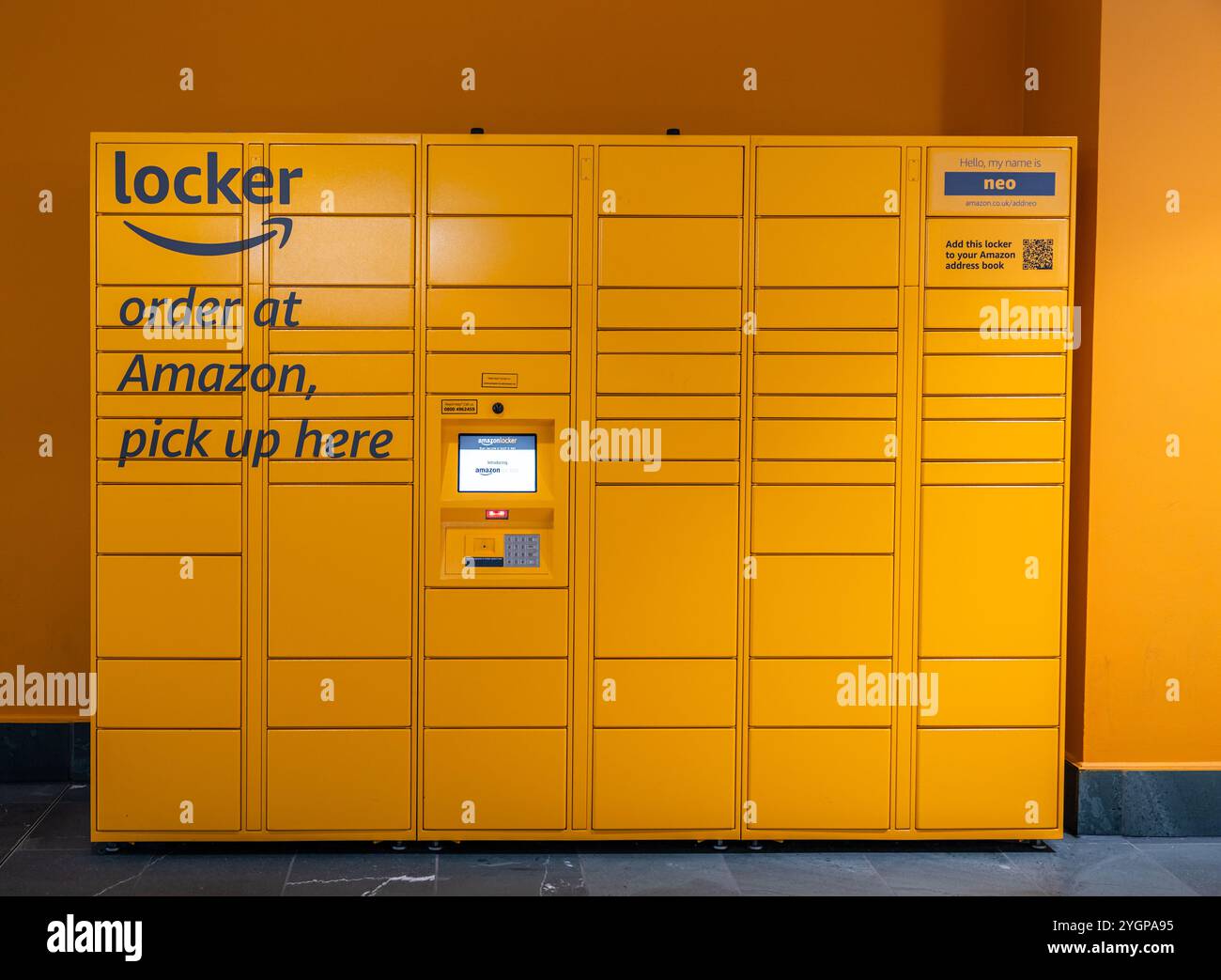 Orangefarbene Amazon Secure Schließfächer in verschiedenen Größen in einem Einkaufszentrum mit auffälligem Amazon Logo. Bestellen Sie bei Amazon, und holen Sie sich hier sichtbar ab Stockfoto