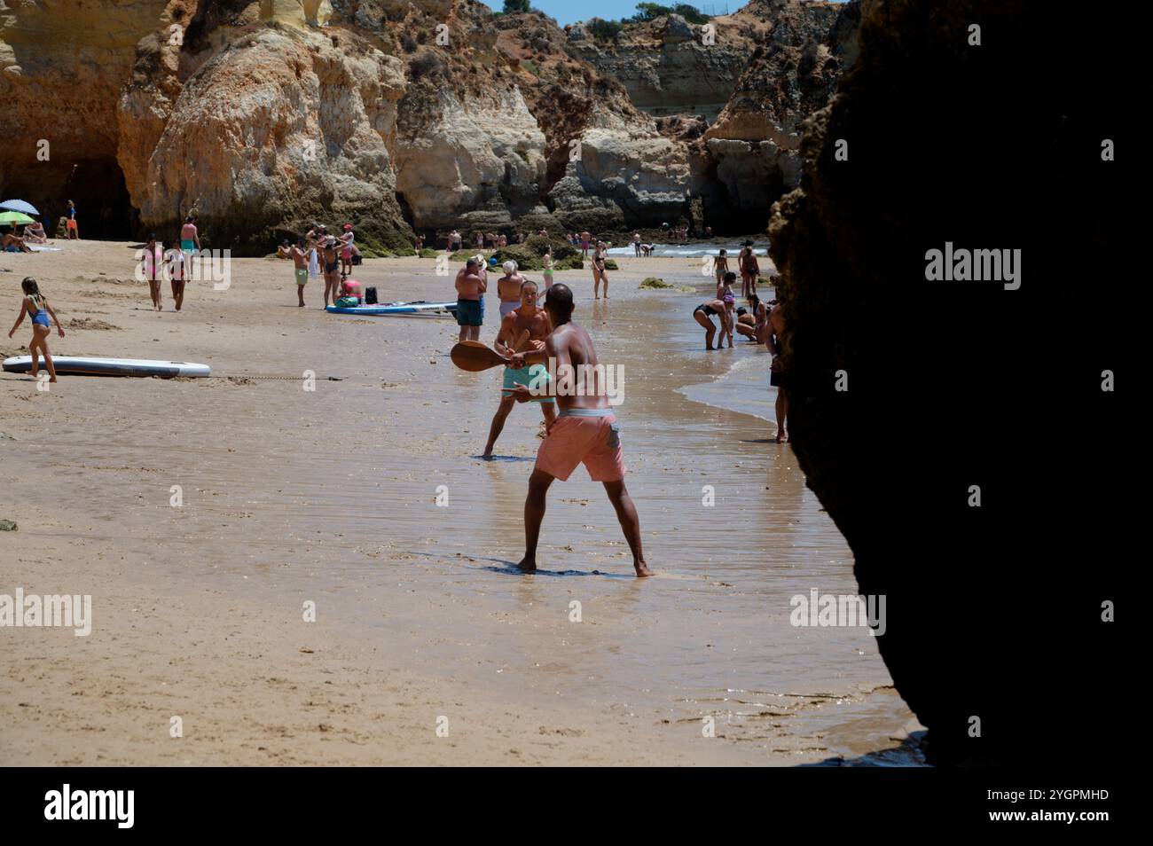 Paare genießen eine Partie Strandpaddeln an der sonnigen Küste von praia da rocha Stockfoto