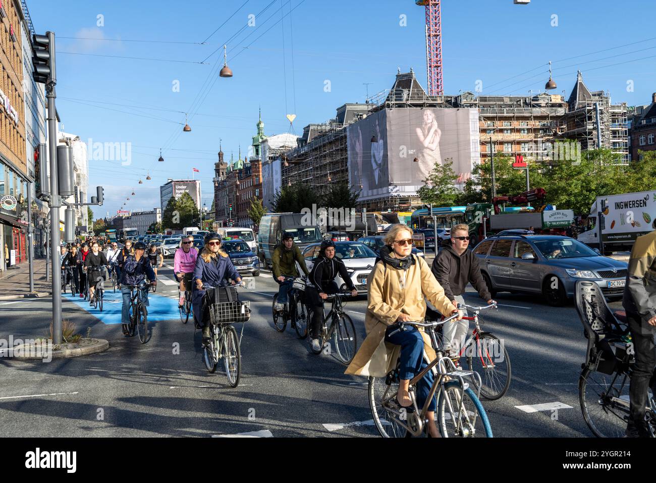 Männer und Frauen, die mit ihren Fahrrädern durch das Stadtzentrum von Kopenhagen fahren, auf einem speziellen Radweg neben Kraftfahrzeugen Stockfoto