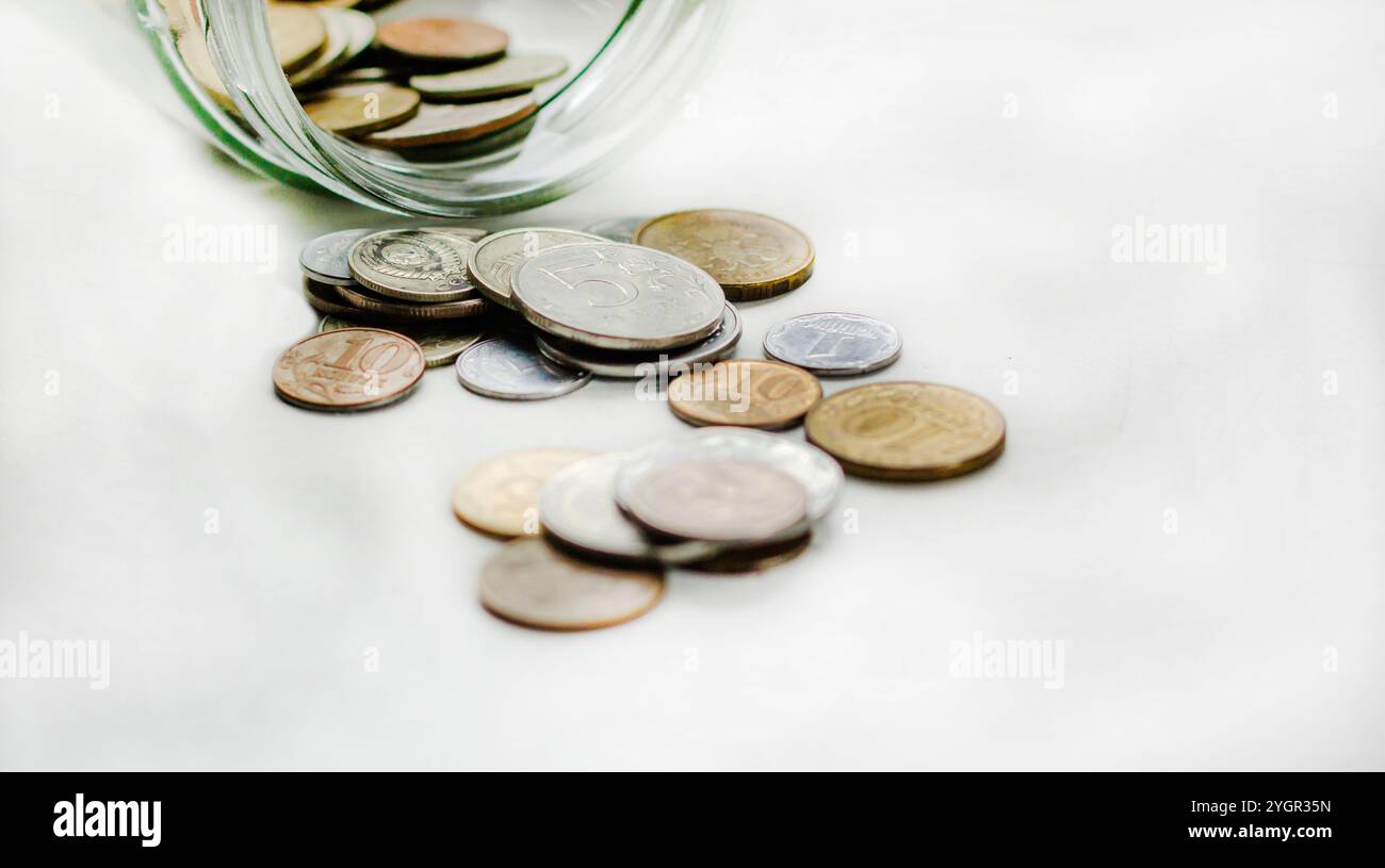 Ein Glasgefäß mit Münzen auf weißem Hintergrund. Wirtschaft und Finanzen Stockfoto