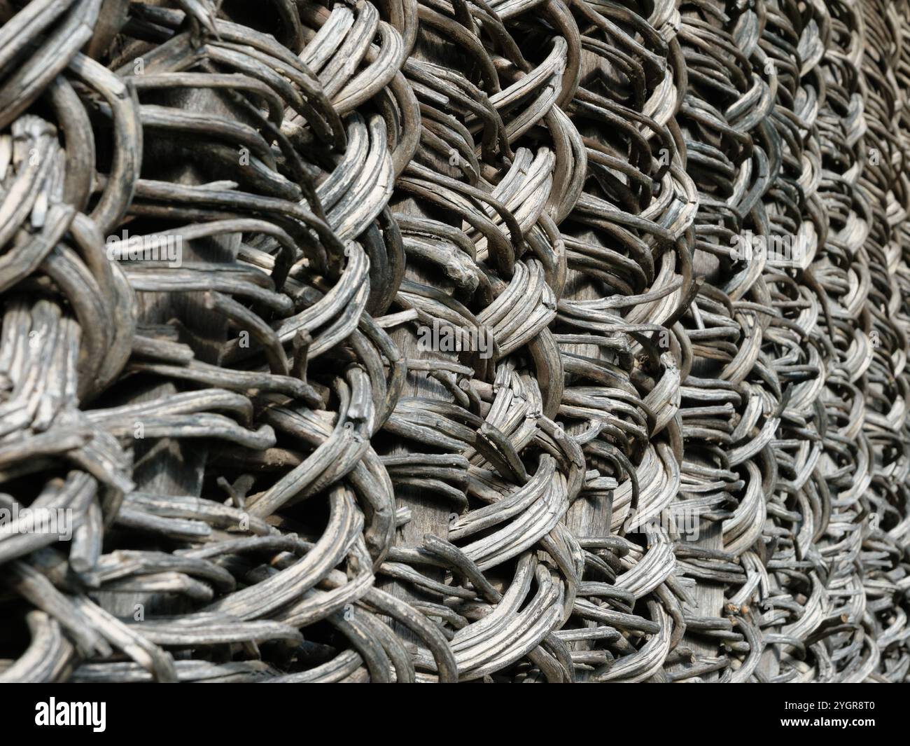 Ein aufwendig gewebter Naturzaun Hintergrund. Alte rustikale Zaunstruktur aus natürlichen Materialien. Stockfoto