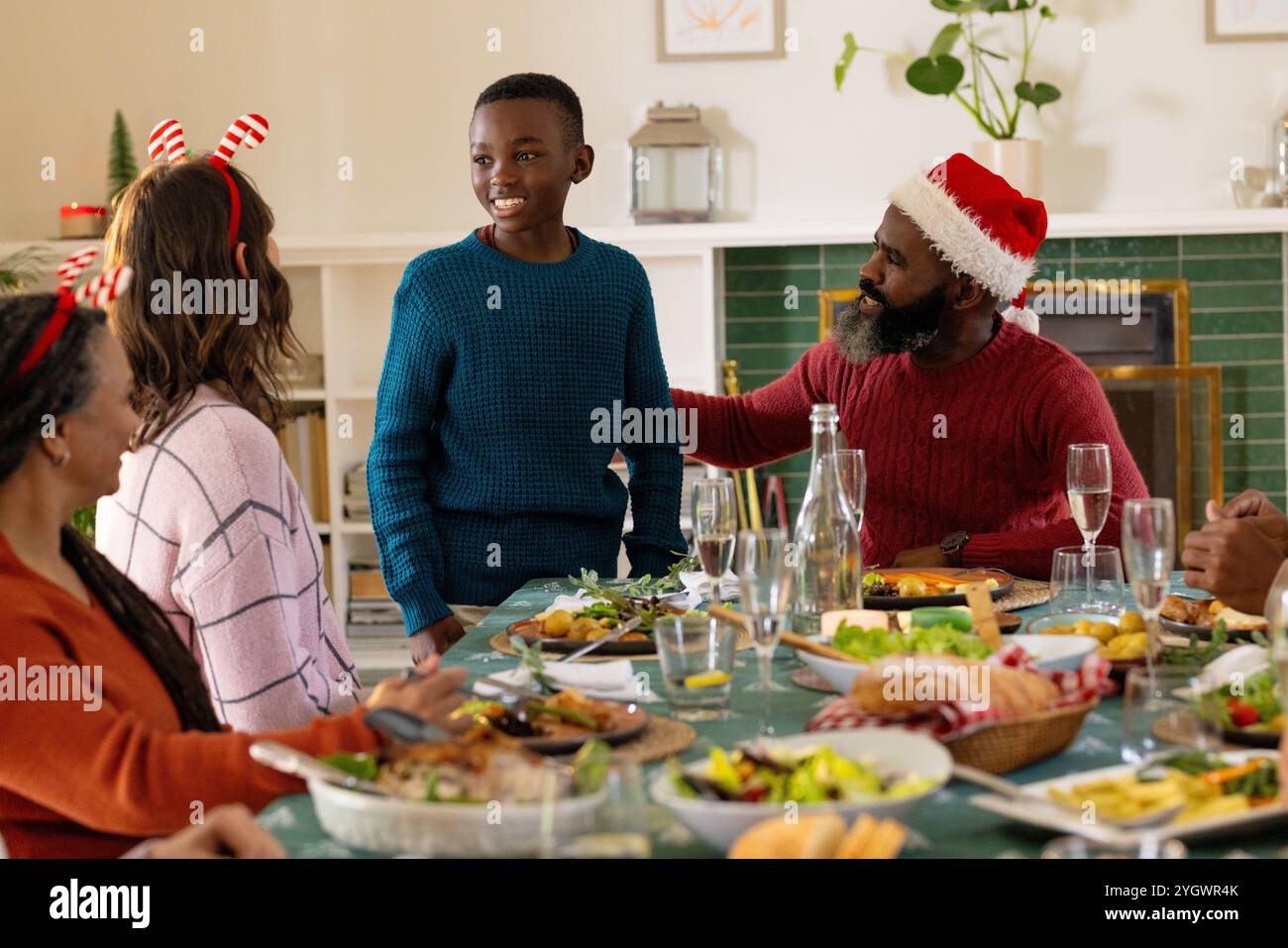 Weihnachtsessen, Familie mit mehreren Rassen, die festliche Mahlzeit und gemeinsames Lachen zu Hause genießen Stockfoto