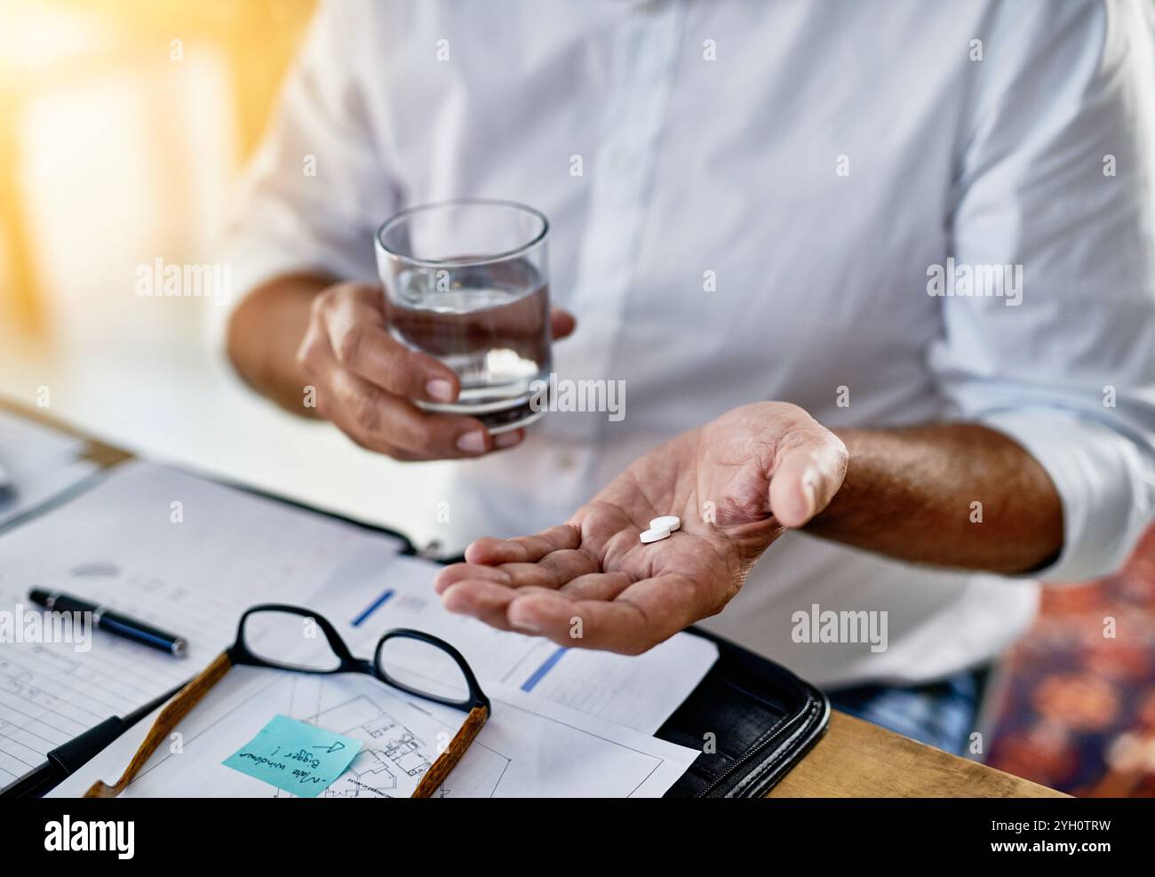 Geschäftsmann, Trinkwasser und Hände mit Pillen zur Medikamentendosierung, Schmerzmitteln oder Medikamenten. Migräne, Papierkram oder Finanzberater mit Tabletten Stockfoto