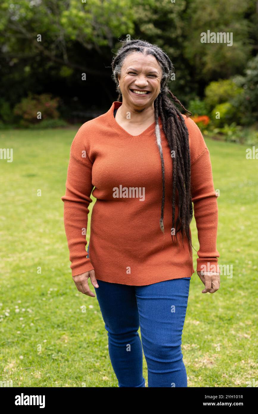 Spazieren im Park, lächelnde Frau mit langen Haaren in lässigem Outfit Stockfoto