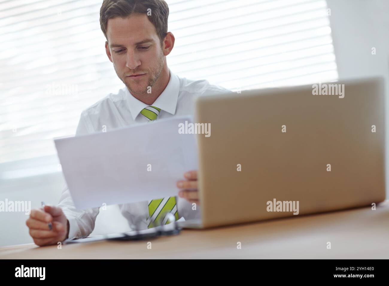 Geschäftsmann, Laptop und Lesedokumente für Finanzberichte, Verträge und kpi-Zusammenfassung im Büro. Unternehmensmitarbeiter, Technologie und Papierkram für Stockfoto